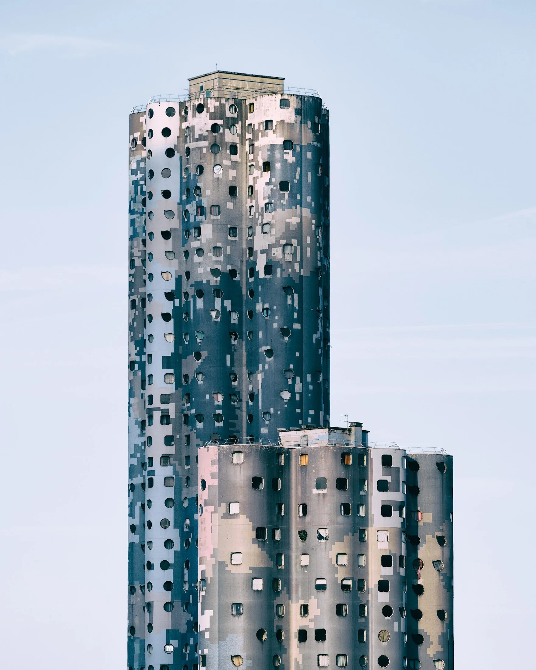 Modernist residential architecture in Nanterre, Paris: A dramatic monochromatic study of the Tours Aillaud (Tours Nuages), designed by Émile Aillaud. This architectural photograph captures the distinctive, organic cylindrical forms of the towers and 