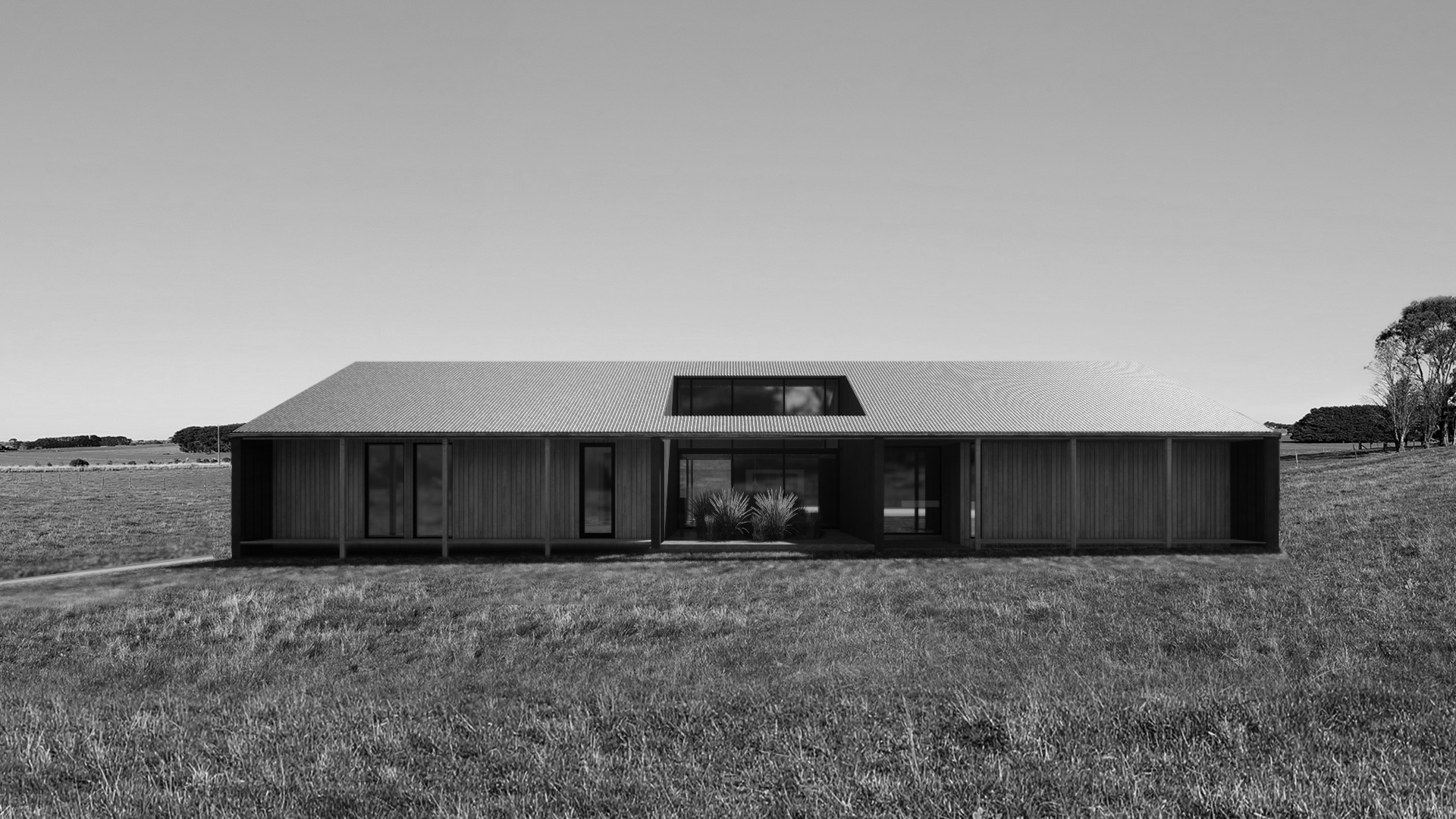 Sustainable rural home in Wangoom featuring a central glazed entrance connecting living zones. The design utilizes durable metal cladding and indoor planting to blend modern architecture with the Surf Coast landscape.