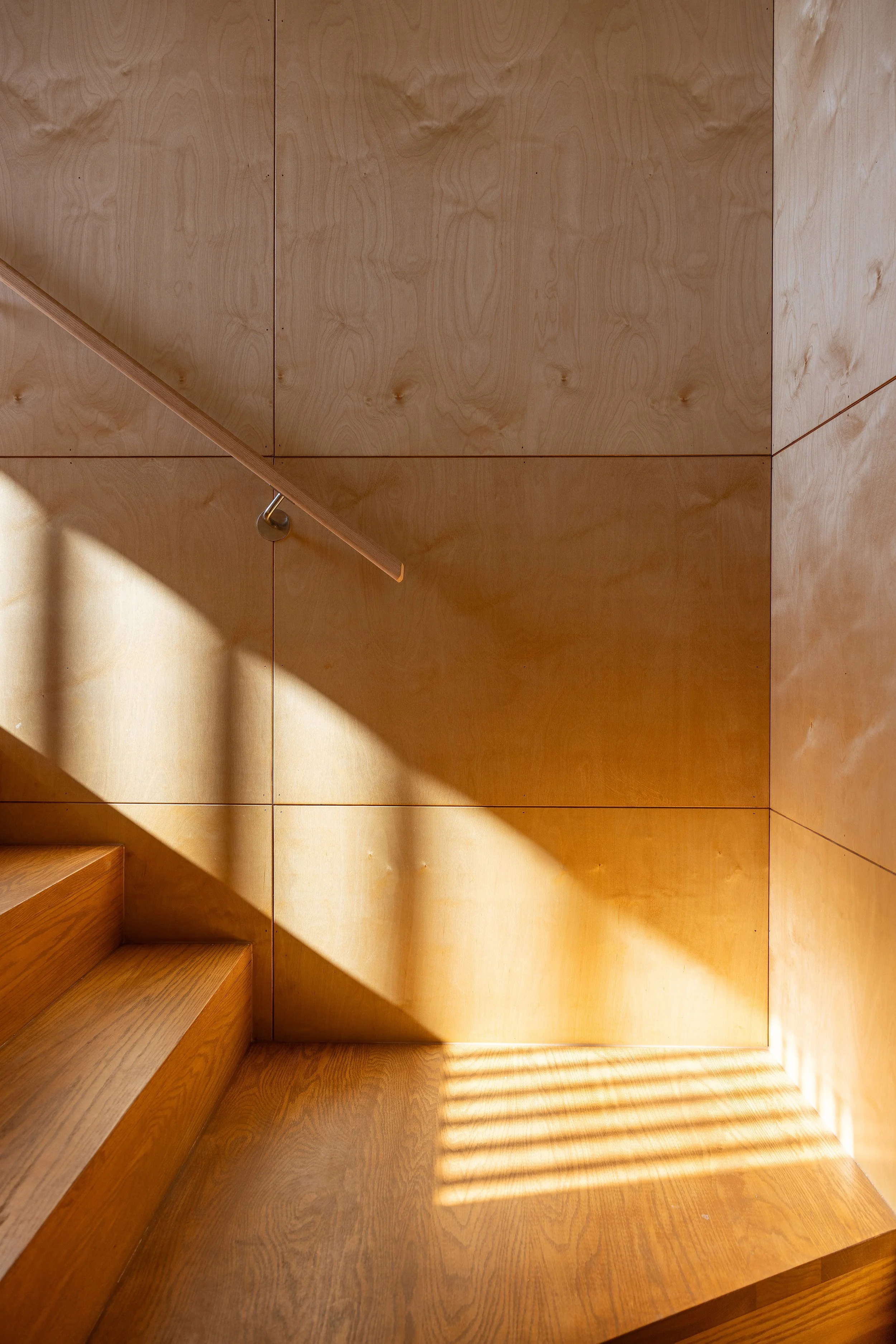 Detail of custom timber staircase with sunlight filtering through blinds in a Port Fairy architectural home.