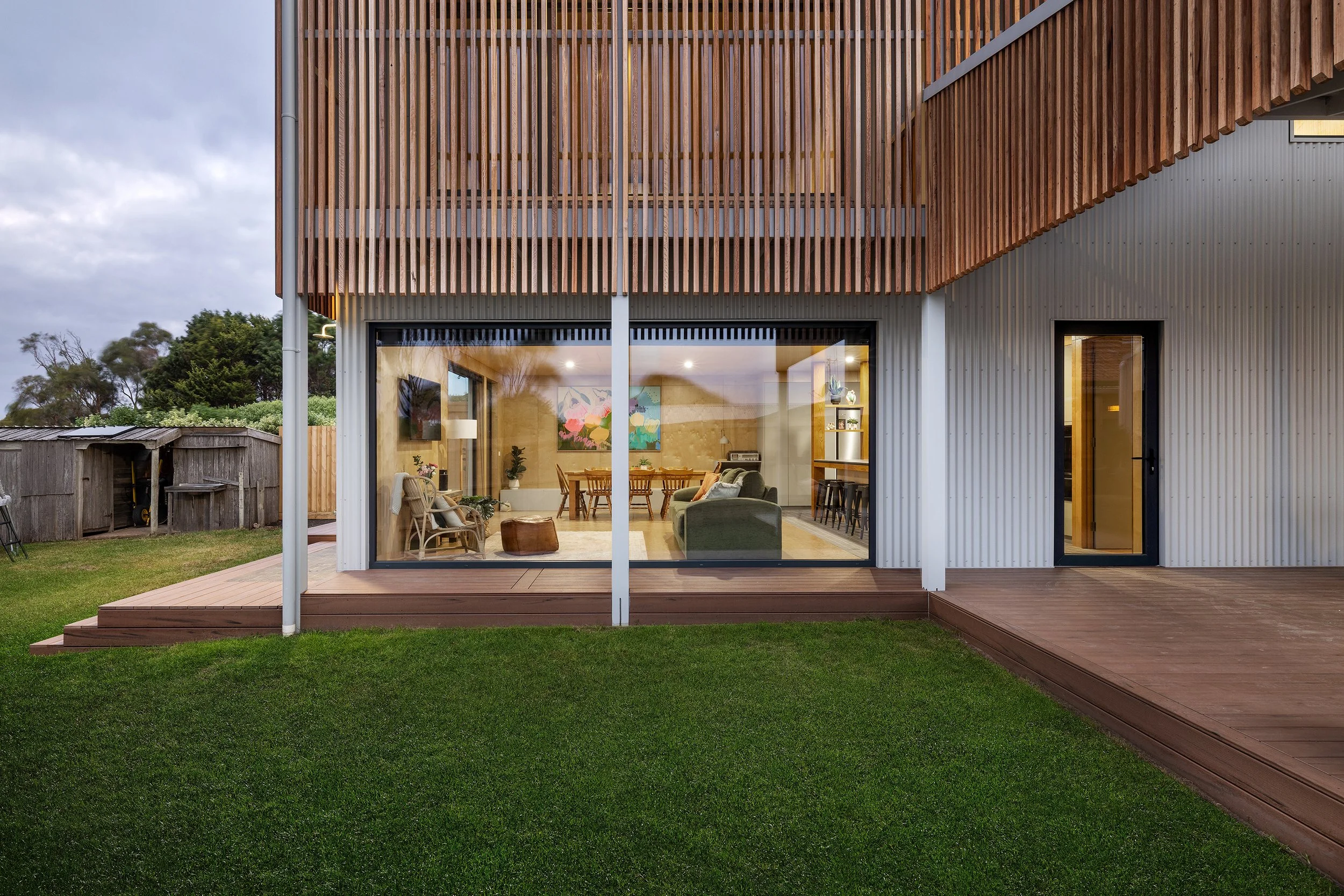Modern PassivHaus coastal home design in Port Fairy featuring sustainable timber siding, large double-glazed windows, and a seamless connection to the backyard deck.