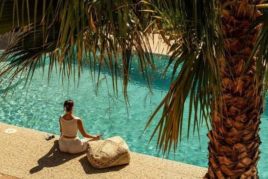 People practicing yoga on a yoga retreat in menorca in a rustic studio or yoga shala with stone walls, wooden ceiling beams, and open windows overlooking greenery