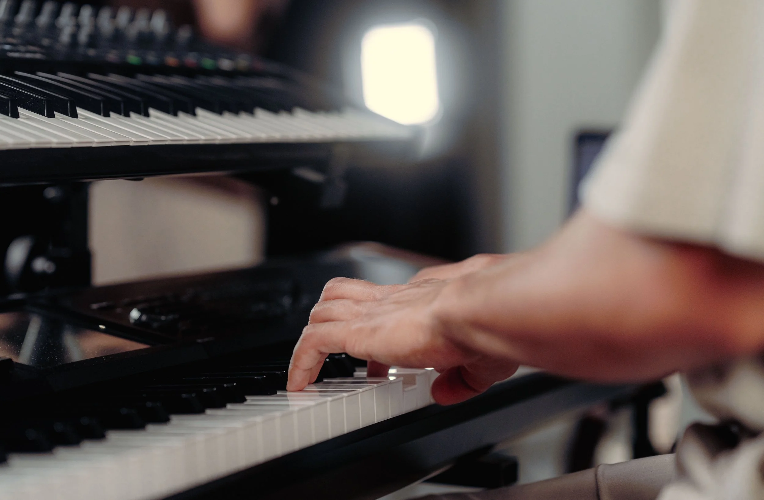Hand eines Pianisten spielt Klavier bei einer Hochzeitszeremonie mit weicher Hintergrundbeleuchtung