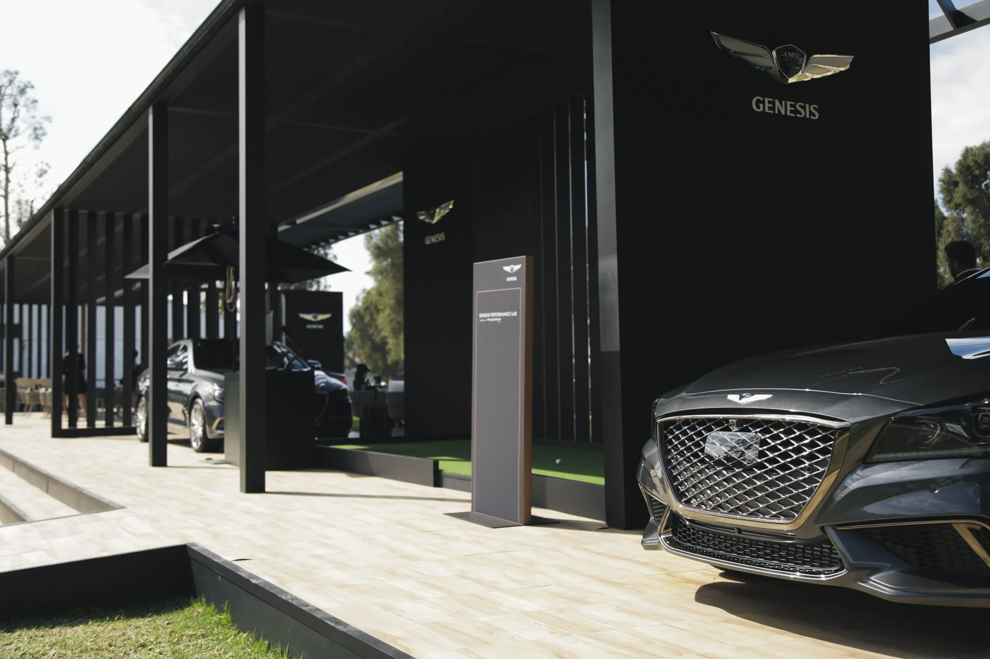 Genesis luxury car display featuring a dark sedan under a modern black outdoor pavilion