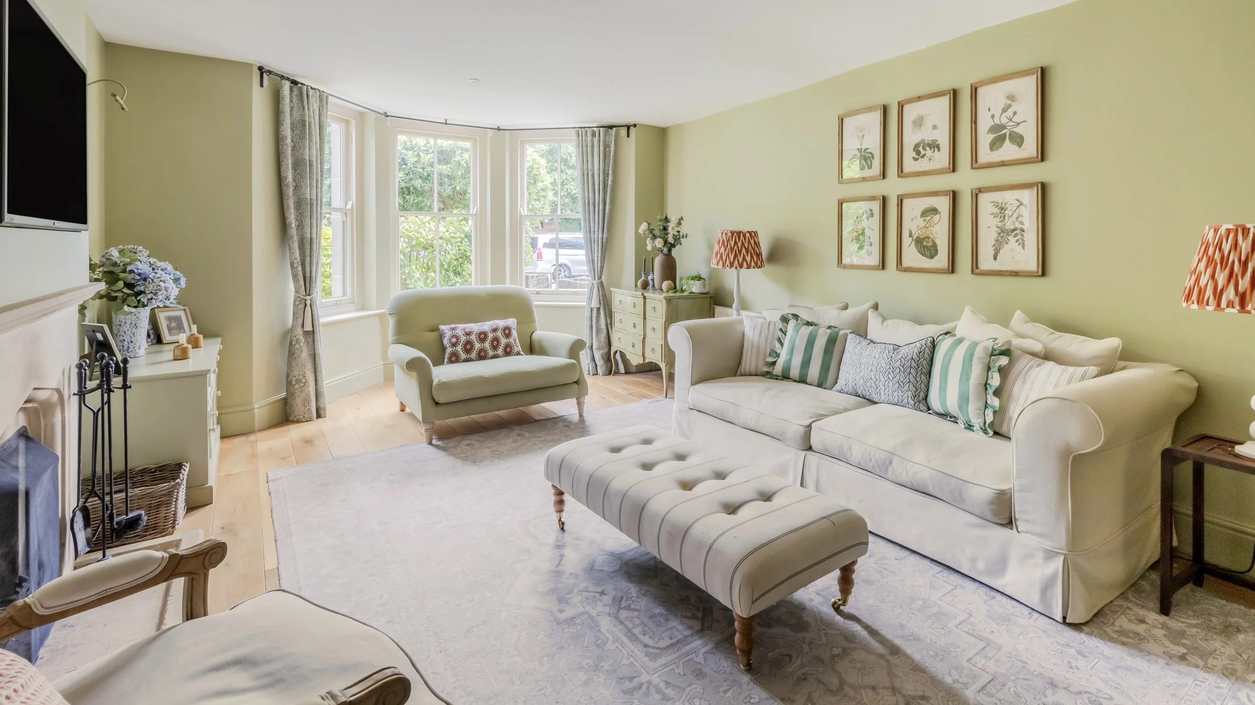 Scenic view of a lake surrounded by green hills and large mountains under a cloudy sky.