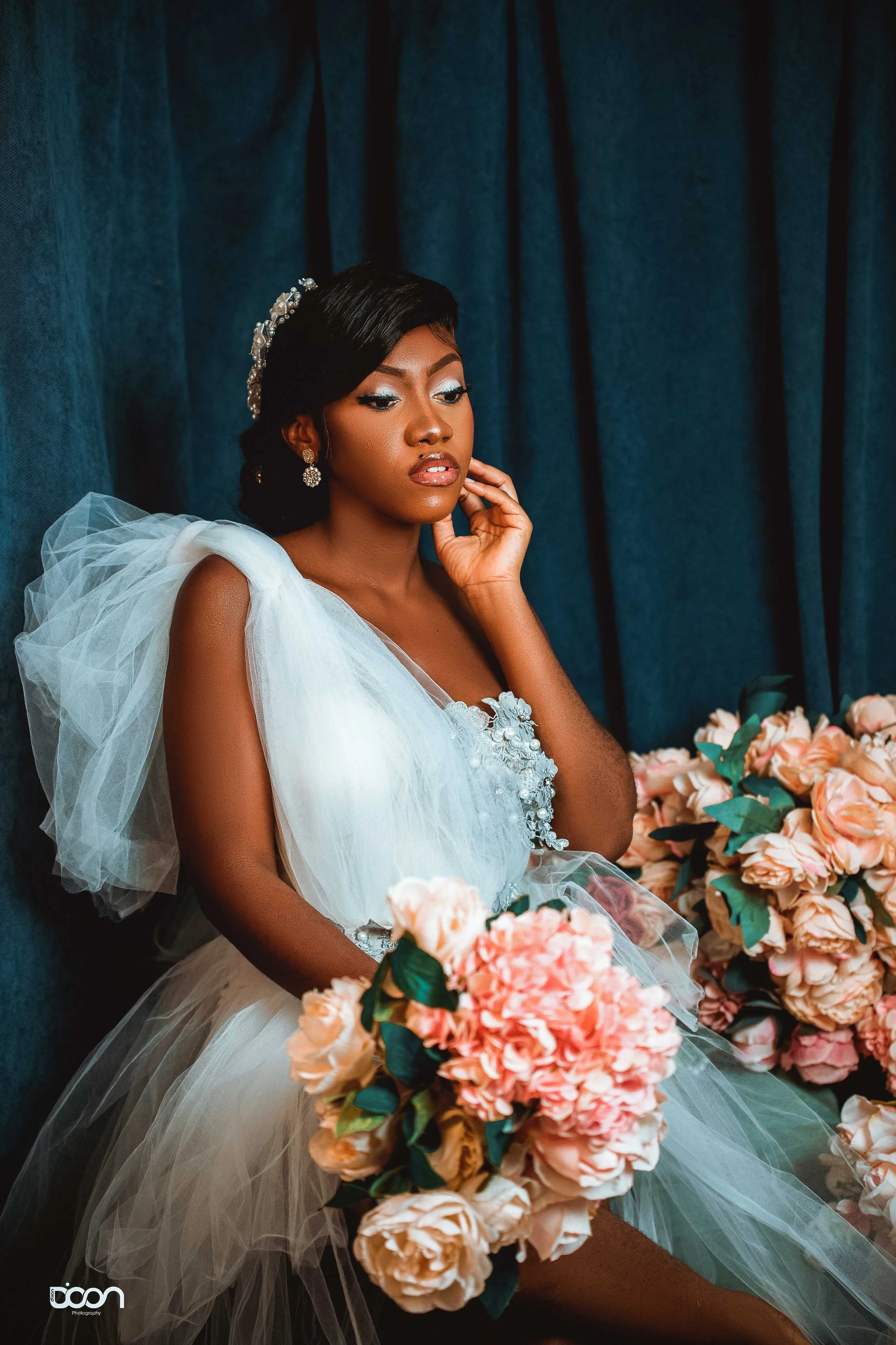 A woman in a wedding dress sitting with pink roses around her