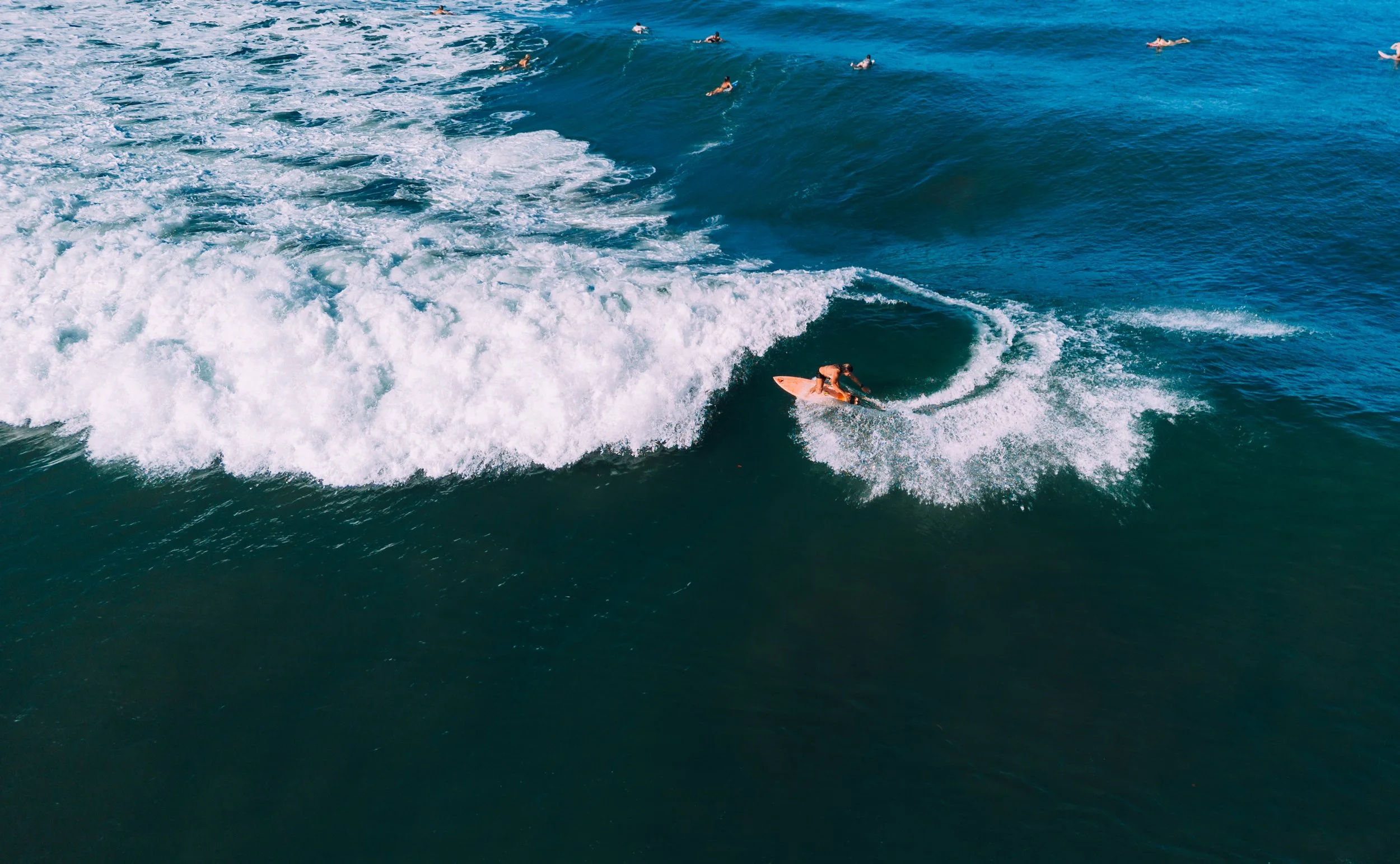 A person surfing on a wave near a rocky shoreline at night.