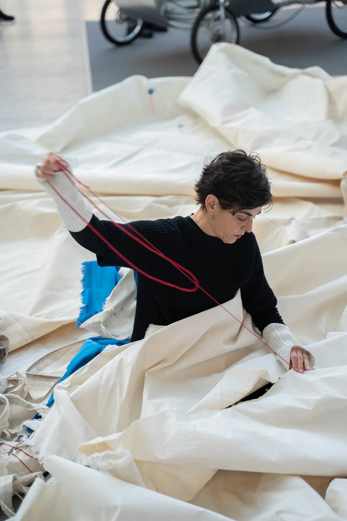 Artista che lavora con grandi pezzi di tessuto o tessuto in un ambiente spazioso.