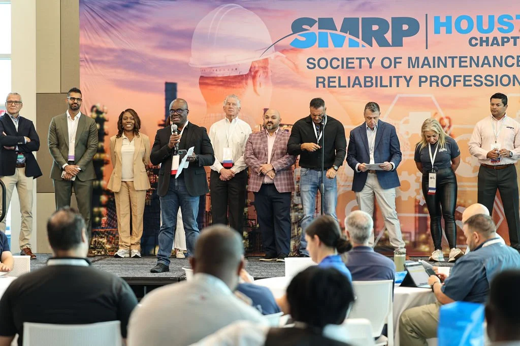 Group of professionals on stage at SMEARP Society of Maintenance Reliability conference, with attendees seated in front, backdrop displays 'SMARP Society of Maintenance Reliability'.
