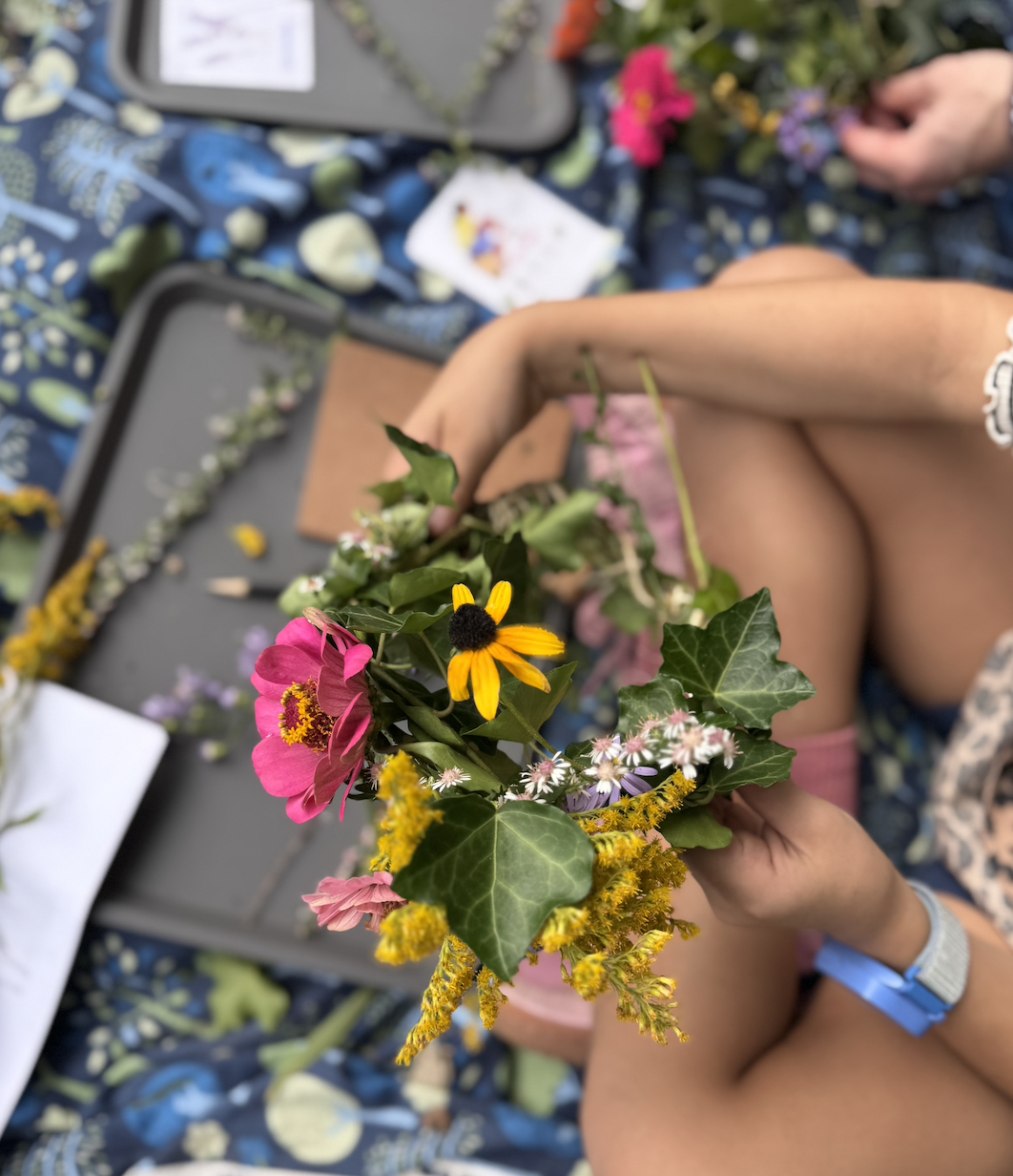 Green magic kids weaving seasonal blooms into a flower crown. 
