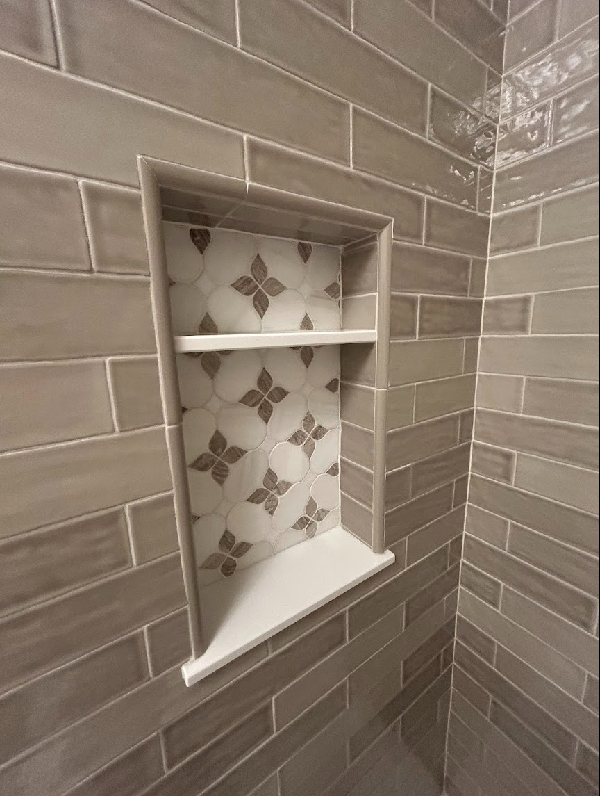 Taupe guest bathroom tile installation in Raleigh, NC featuring glossy wall tile, built-in shower niche, decorative accent tile, and precision craftsmanship by Parker’s Precision Tile.
