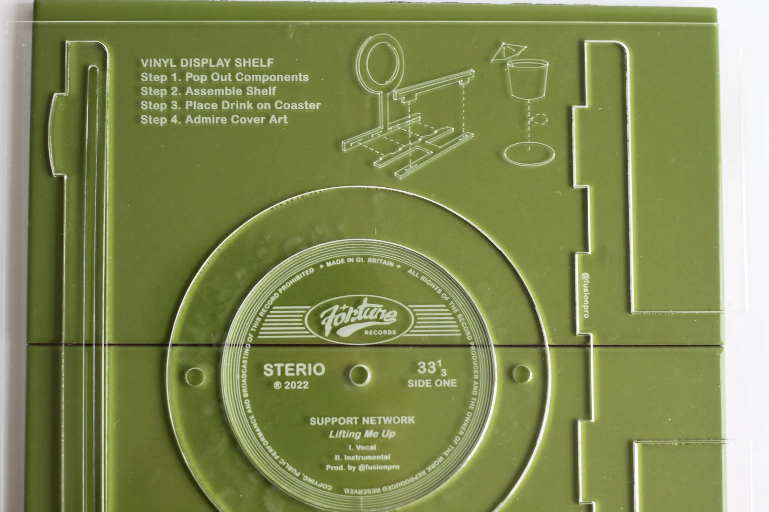Green vinyl record display shelf with instructions for assembly and record label for 'Lifting Me Up' by Support Network, produced in 2022.