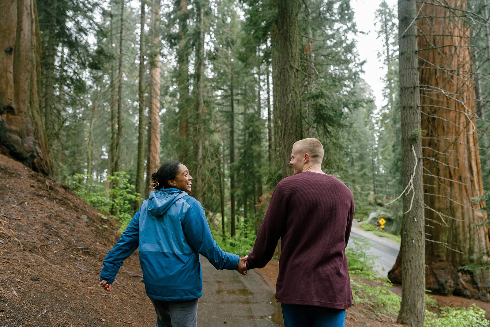Couple holding hands laughing after their Sequoia National Park proposal