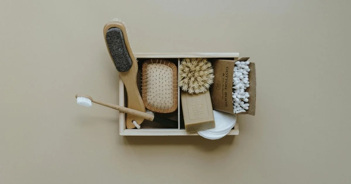 A beige box containing grooming brushes, soap, and cotton swabs, arranged on a beige surface.
