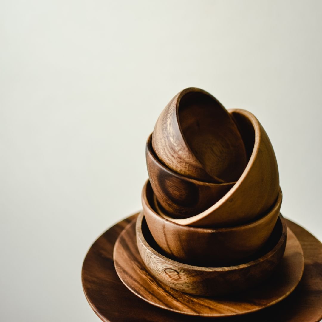 Stacked wooden bowls on a matching wooden plate.