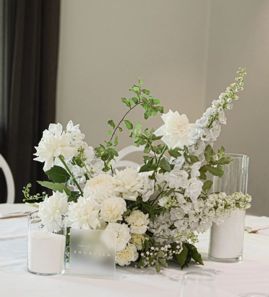 White floral centerpiece with candles on a table.