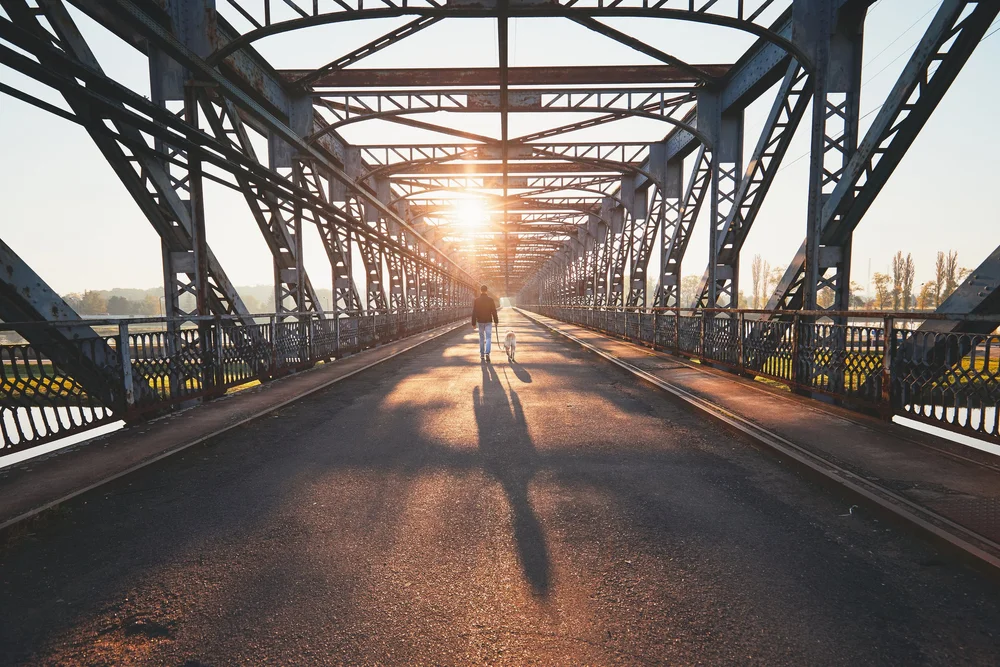 Walking across a bridge at sunrise