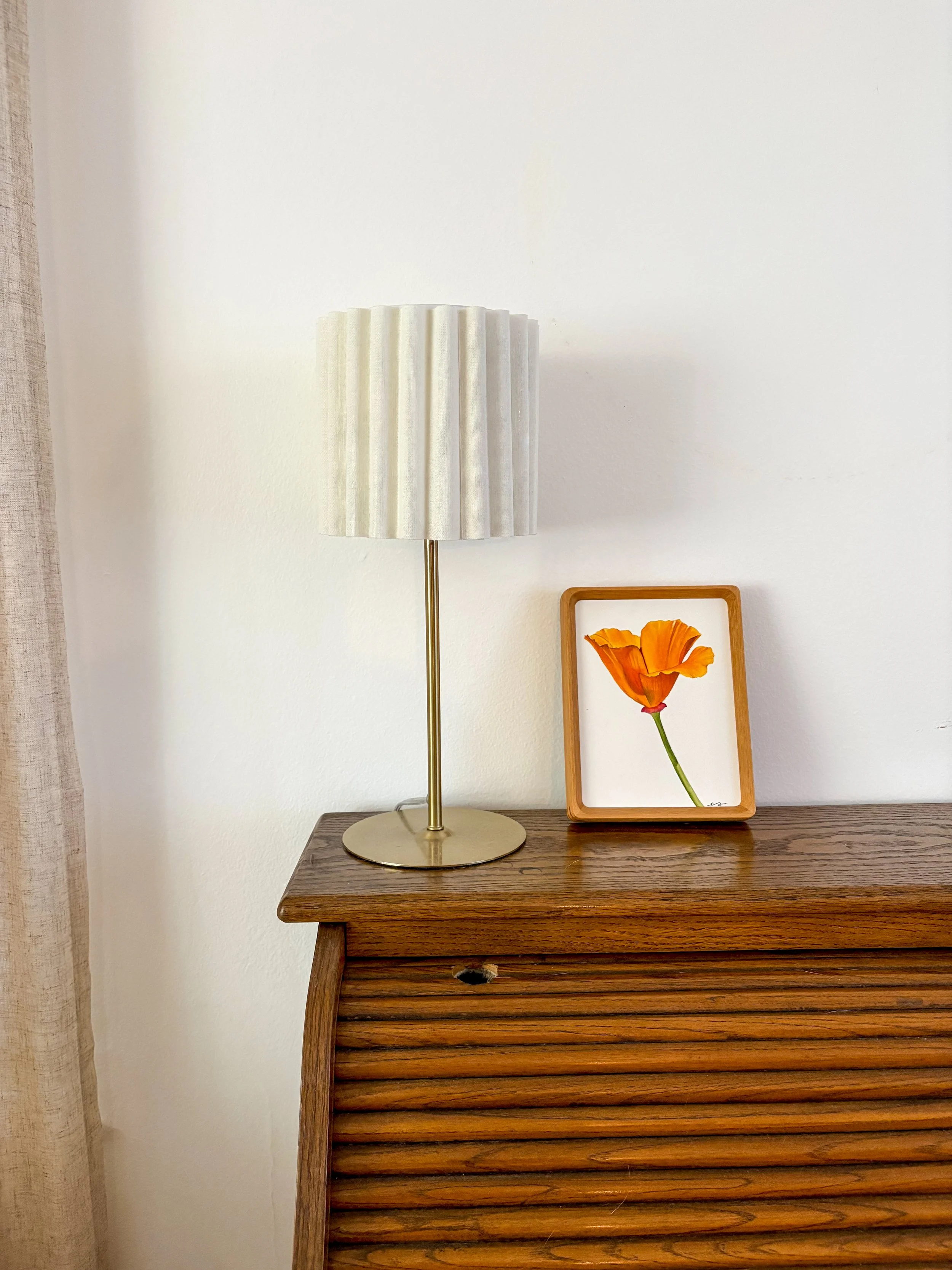 Original small framed watercolor painting of a single California poppy in tangerine orange on a white background, in a warm wood frame