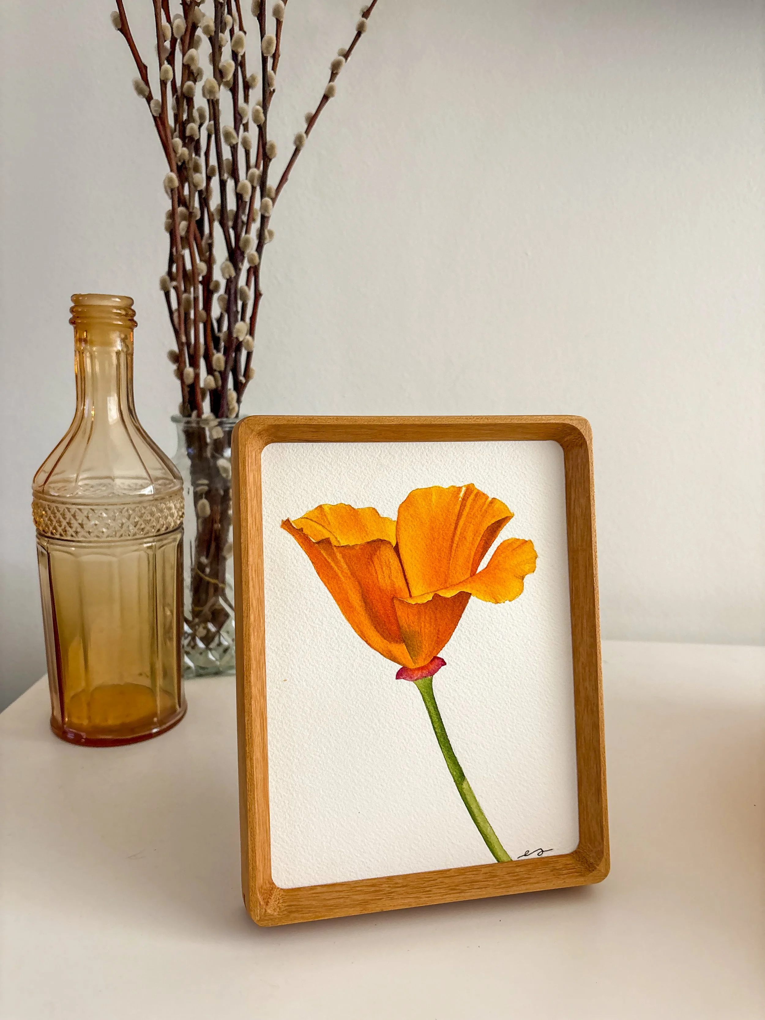 Original small framed watercolor painting of a single California poppy in tangerine orange on a white background, in a warm wood frame