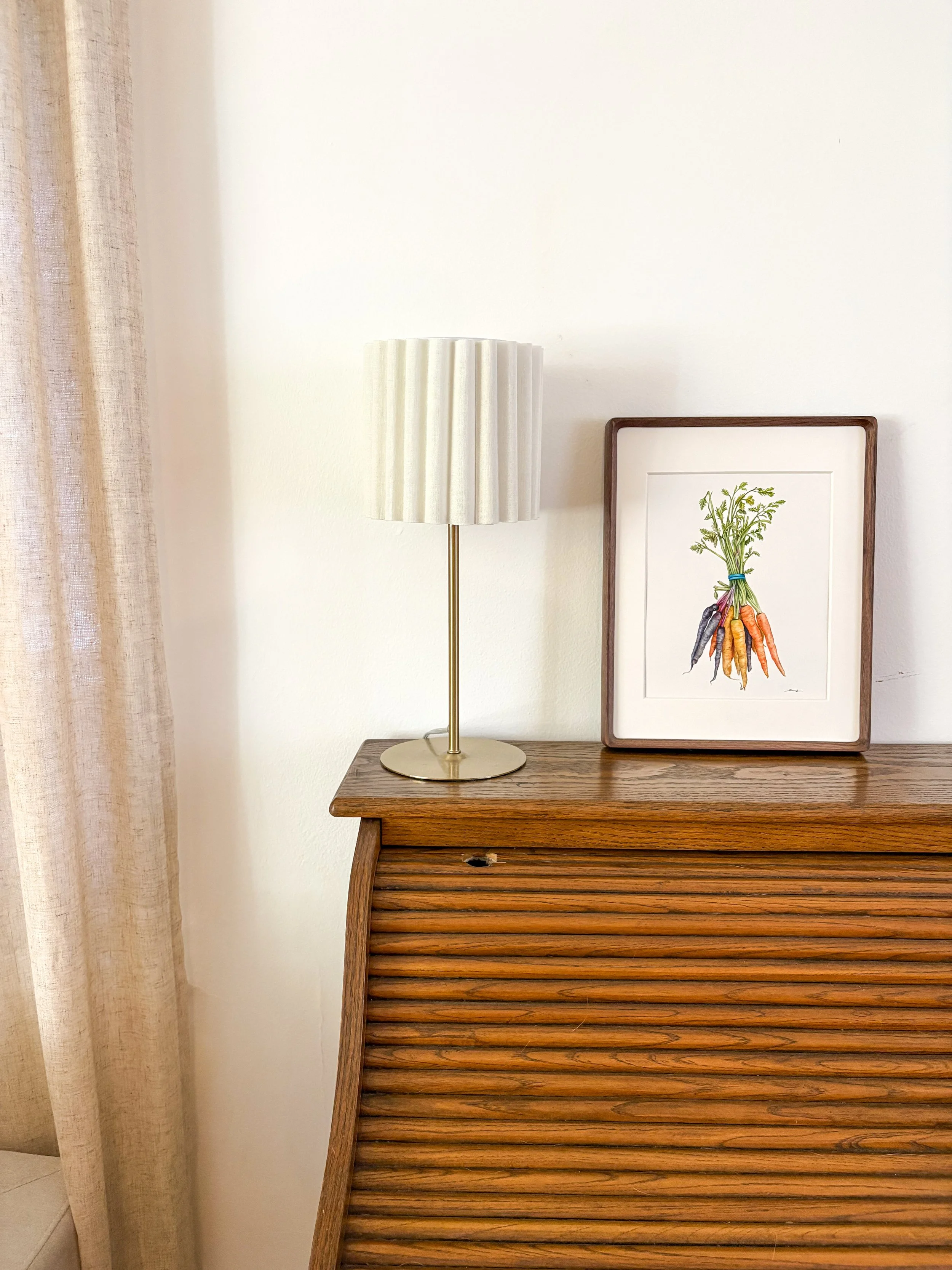 Original framed watercolor painting of a bundle of rainbow carrots in purple, yellow and orange tied with a blue rubber band and green tops, in a dark walnut frame