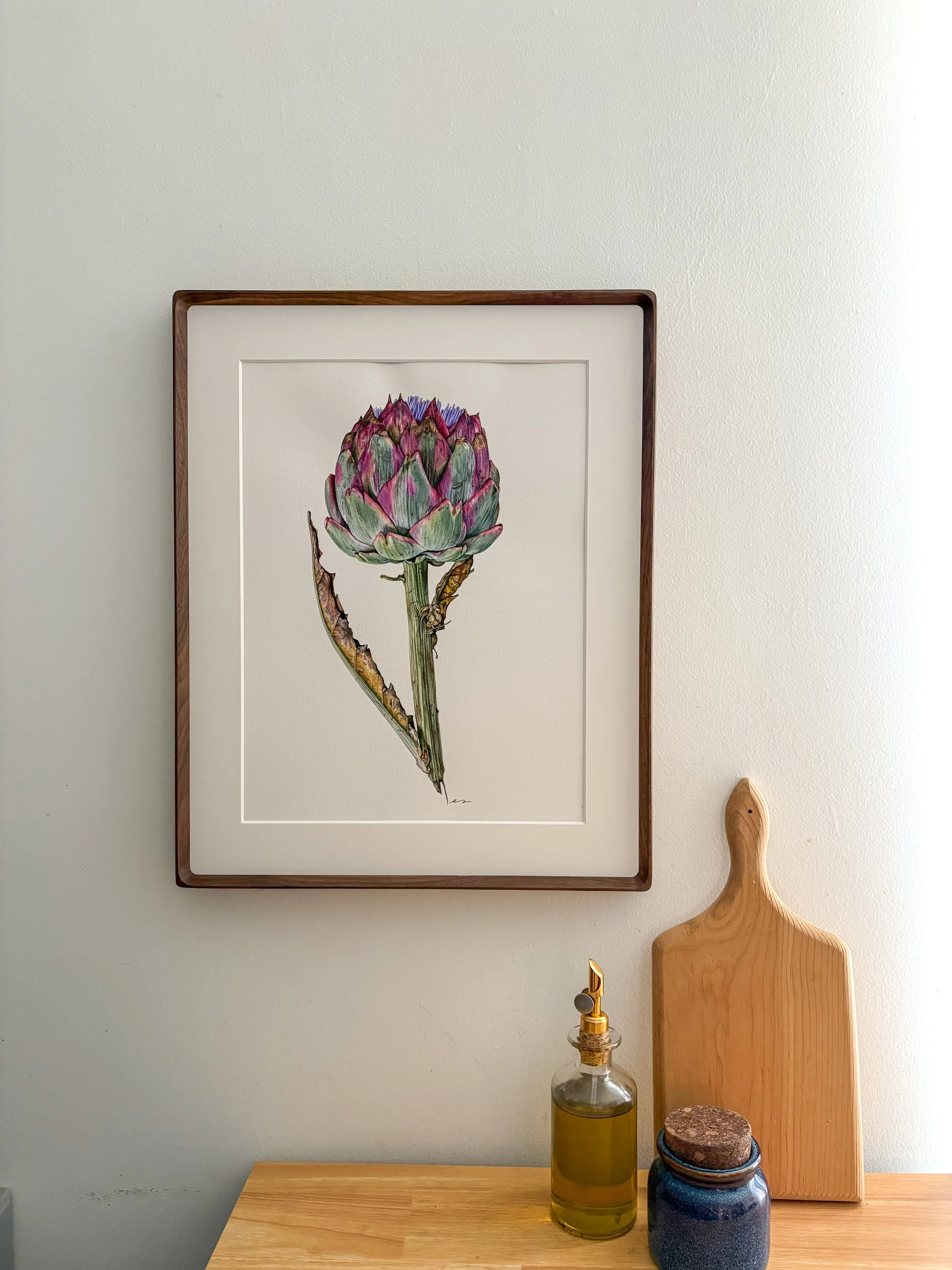 Original framed watercolor painting of a full stem artichoke in sage green and deep purple with a lilac flower at the crown, in a dark walnut wood frame
