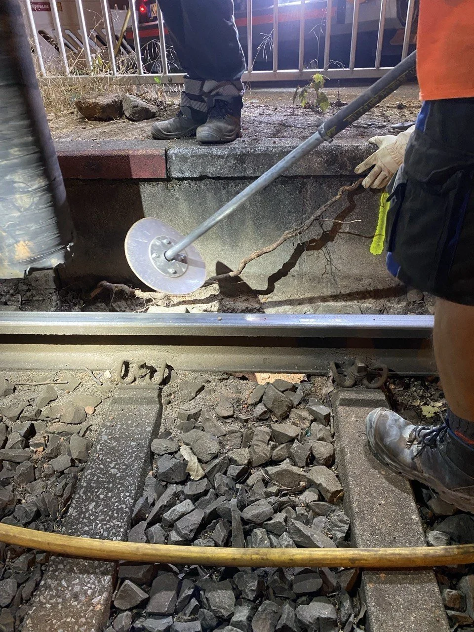 Arbeiter reparieren einen beschädigten Bahnübergang mit einem Gummihammer, Splitter und Steinen um die Schiene.