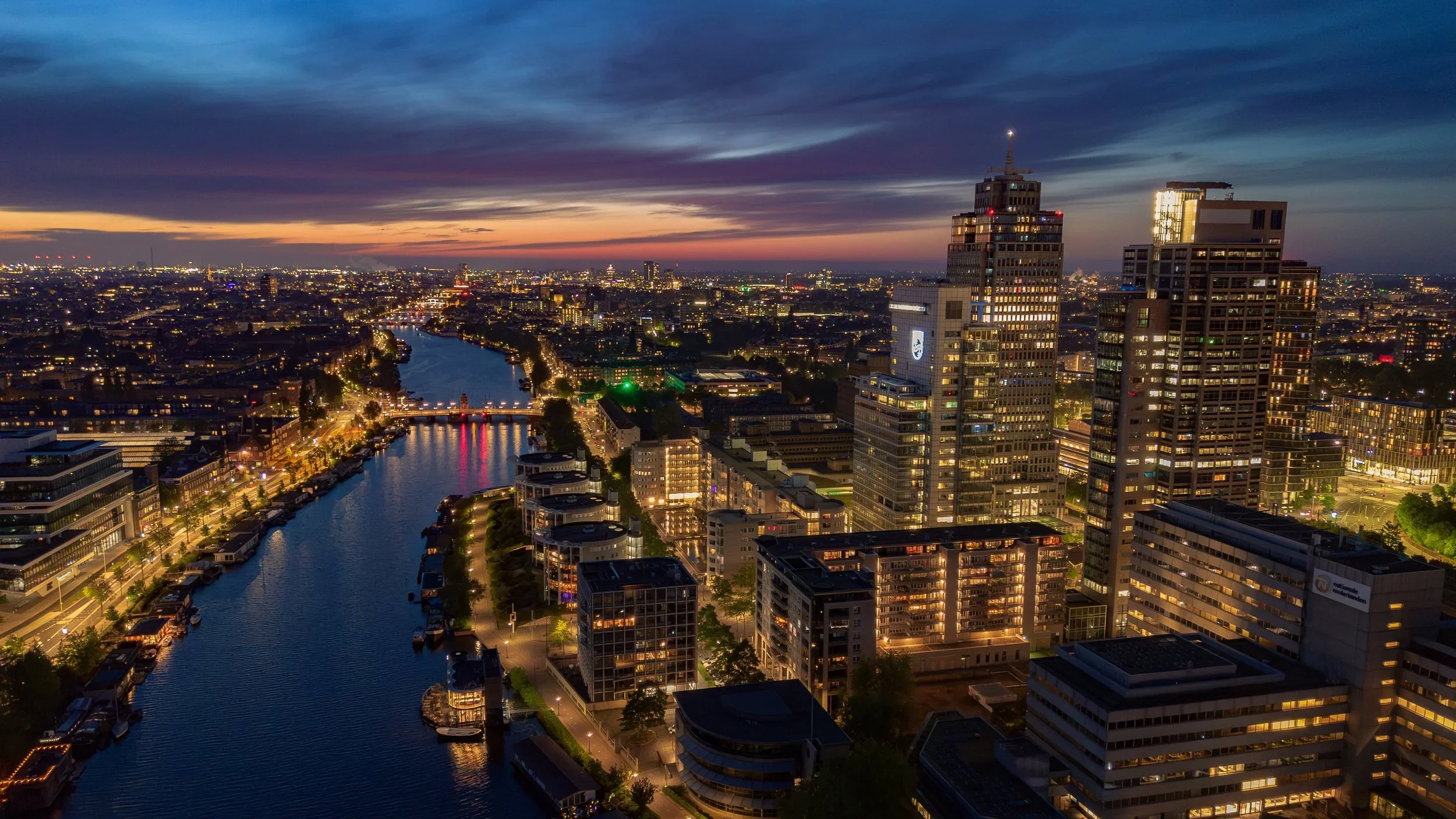 Uitzicht over een Amsterdam bij nacht, uitkijkende over de Amstel.