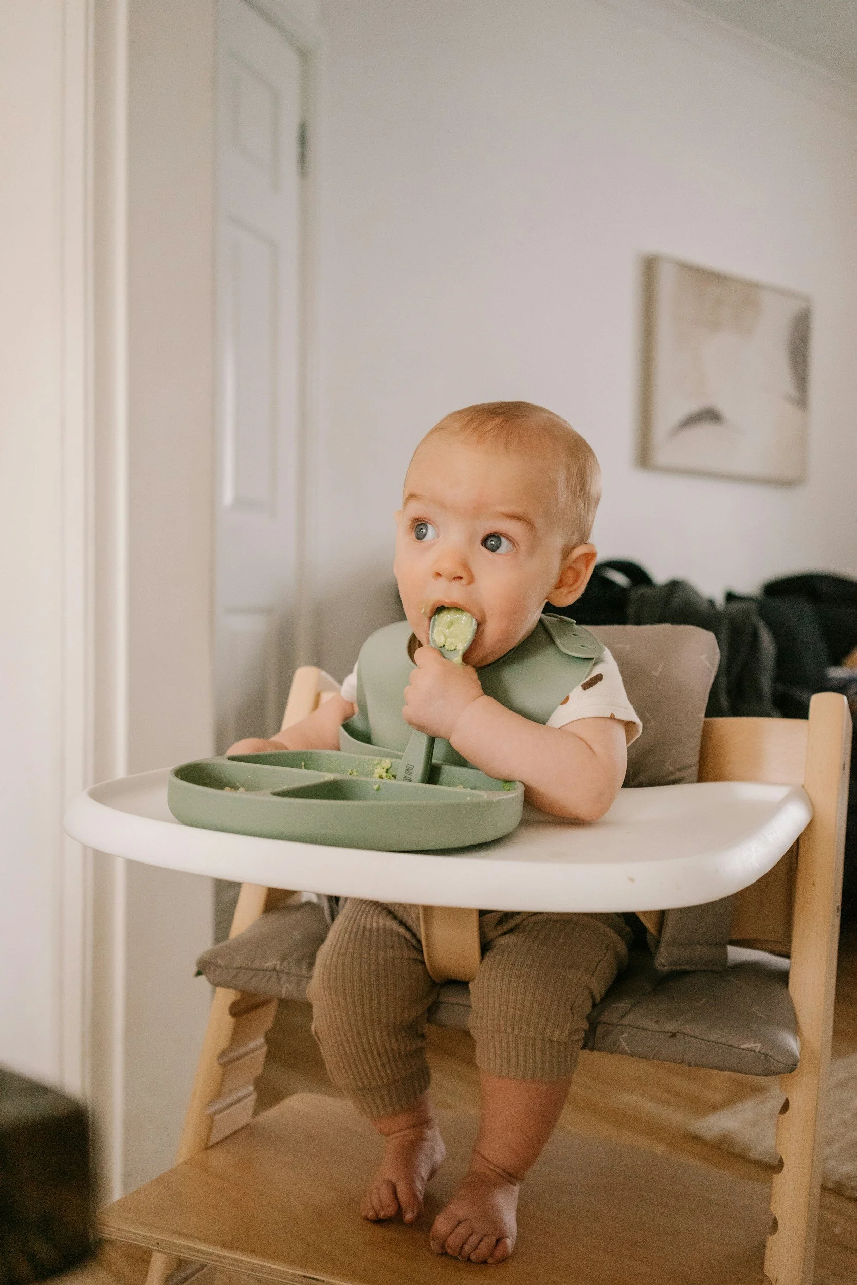 image of a baby feeding themselves while sitting in a high chair