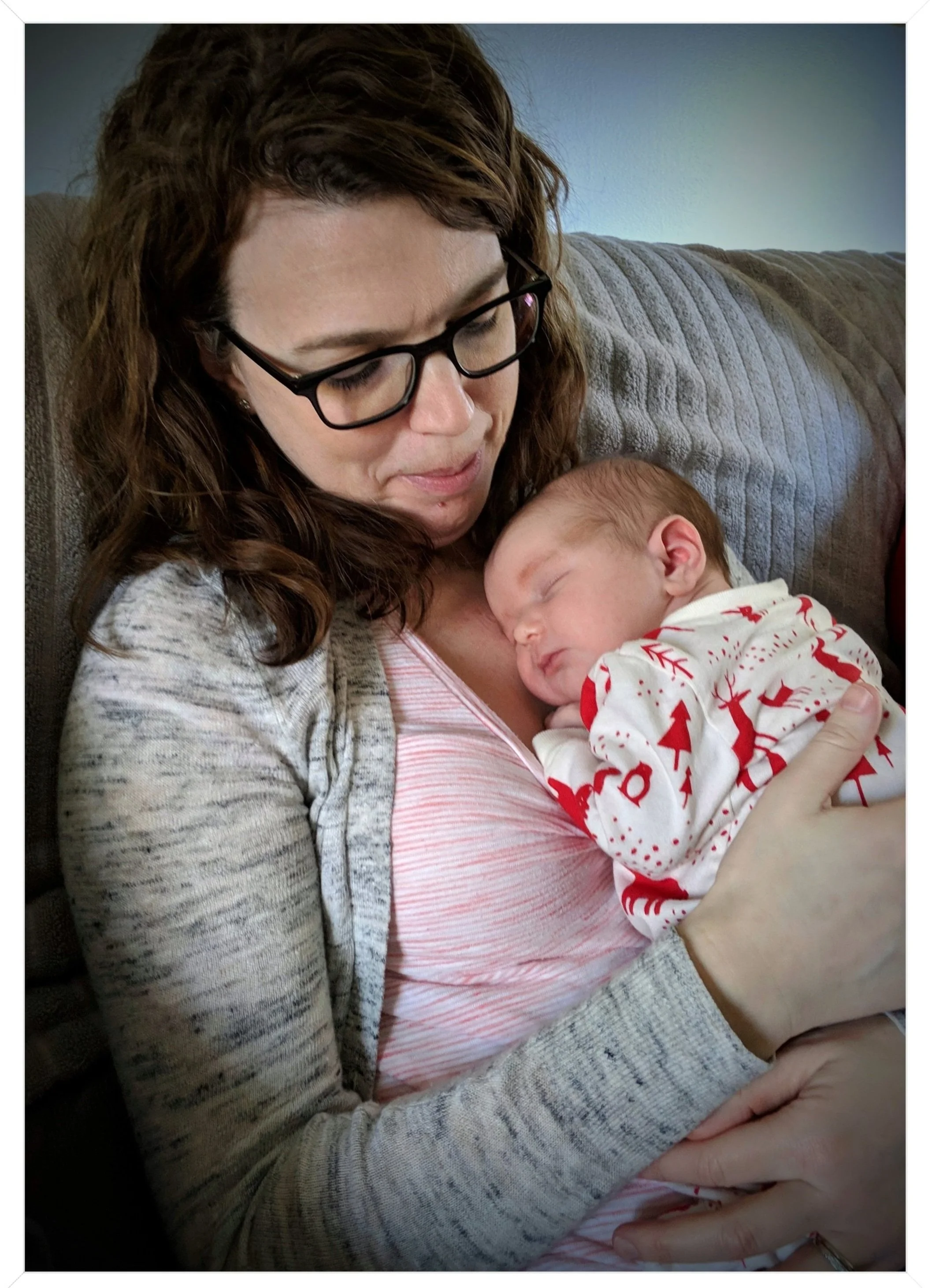 Close-up of Kelly smiling warmly at sleeping newborn