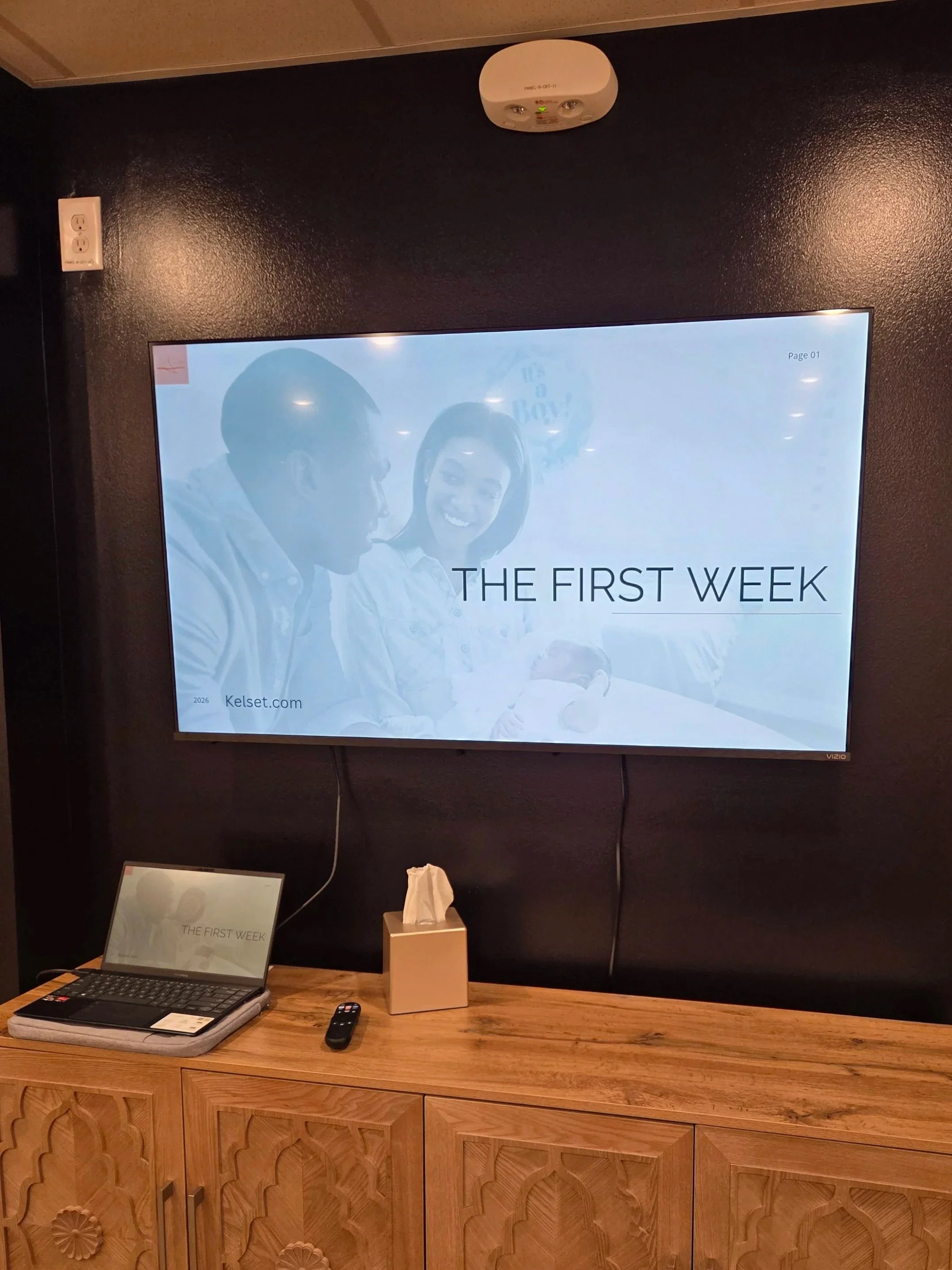 A presentation screen titled 'First Week Home' inside the North Carolina Birth Center classroom.