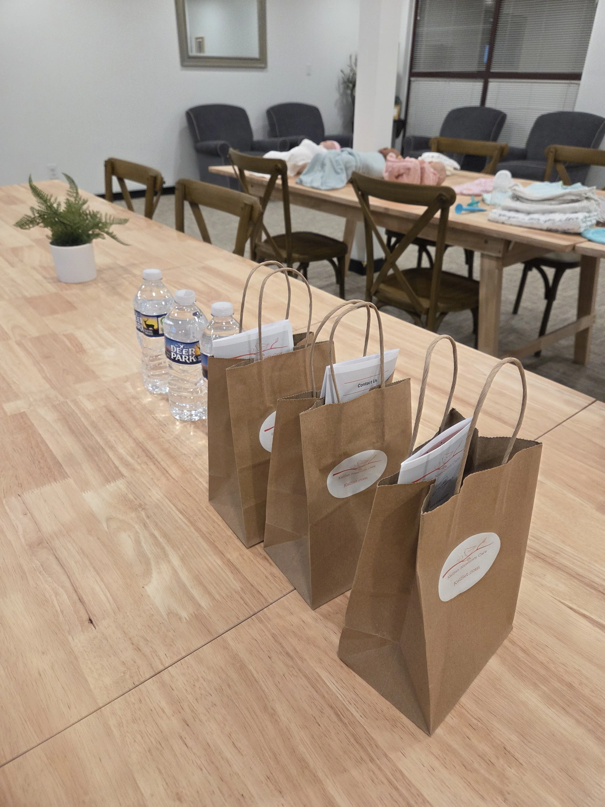 Newborn class setup at the North Carolina Birth Center featuring swaddle demo dolls, student giveaway bags, and refreshments.