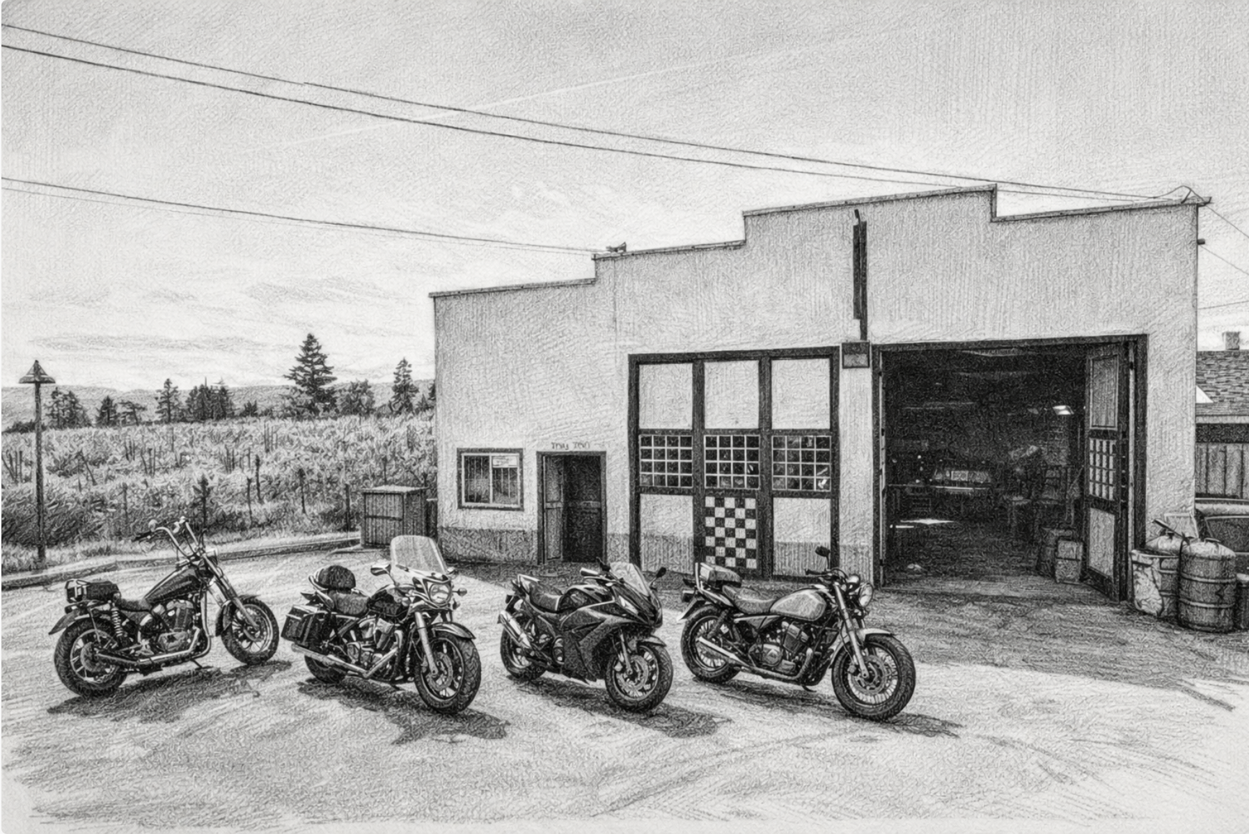 Four motorcycles parked in front of a building with a large garage door and a smaller entrance door, with a scenic landscape and power lines in the background.