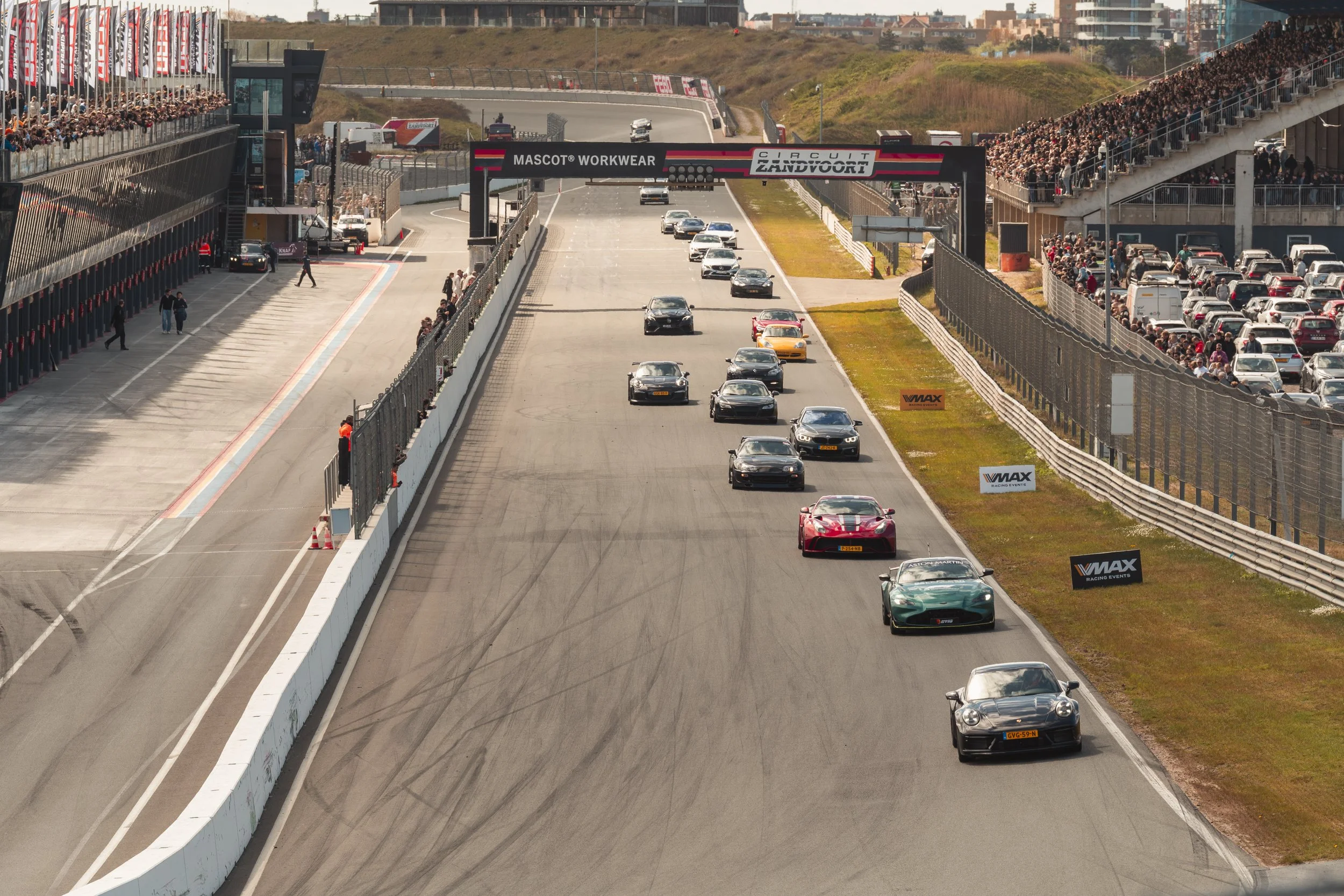 Race cars driving on a race track with spectators watching from grandstands on both sides.
