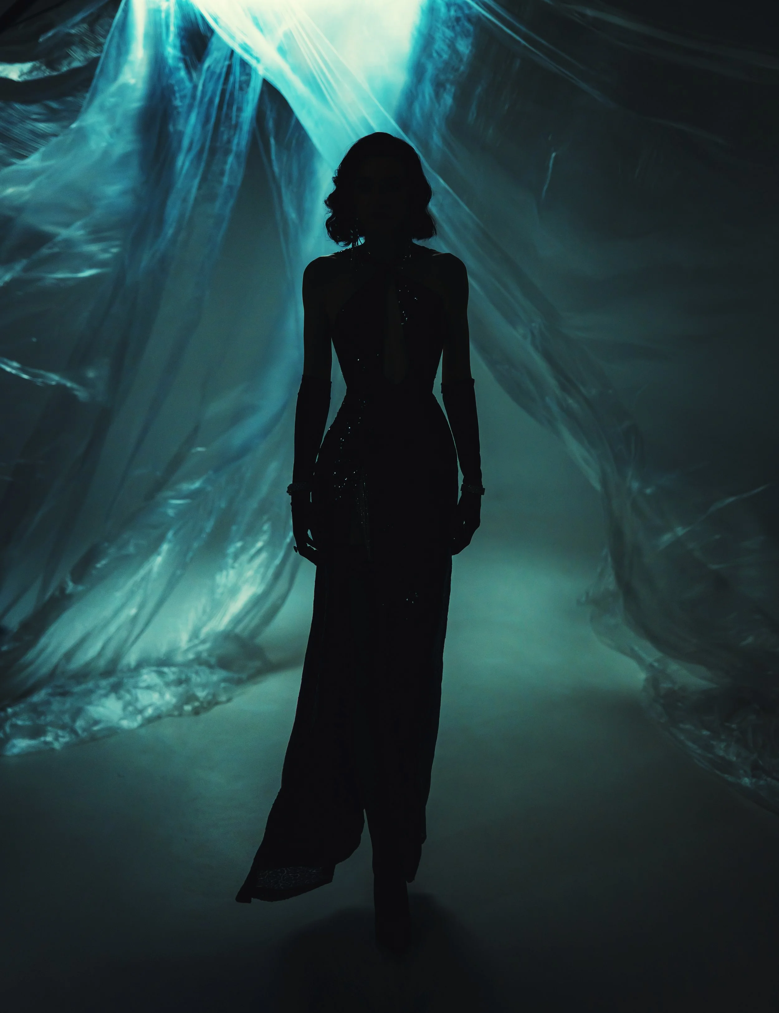 Silhouette of a woman with curly hair standing in front of an abstract, glowing blue-green background with light streaks.