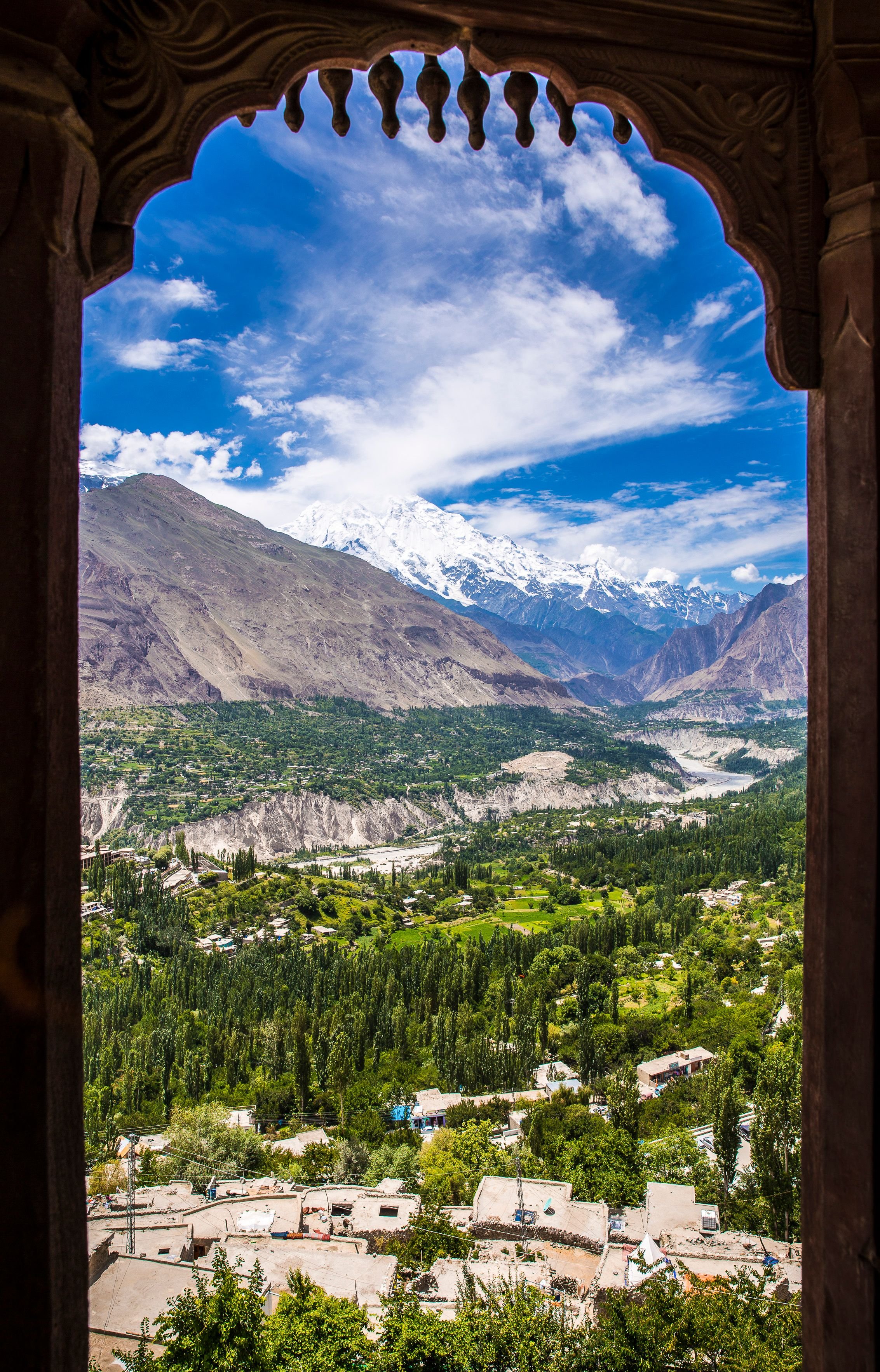 View of Hunza Valley in Gilgit-Baltistan, Pakistan, framed by traditional architecture with the Karakoram mountains in the background.