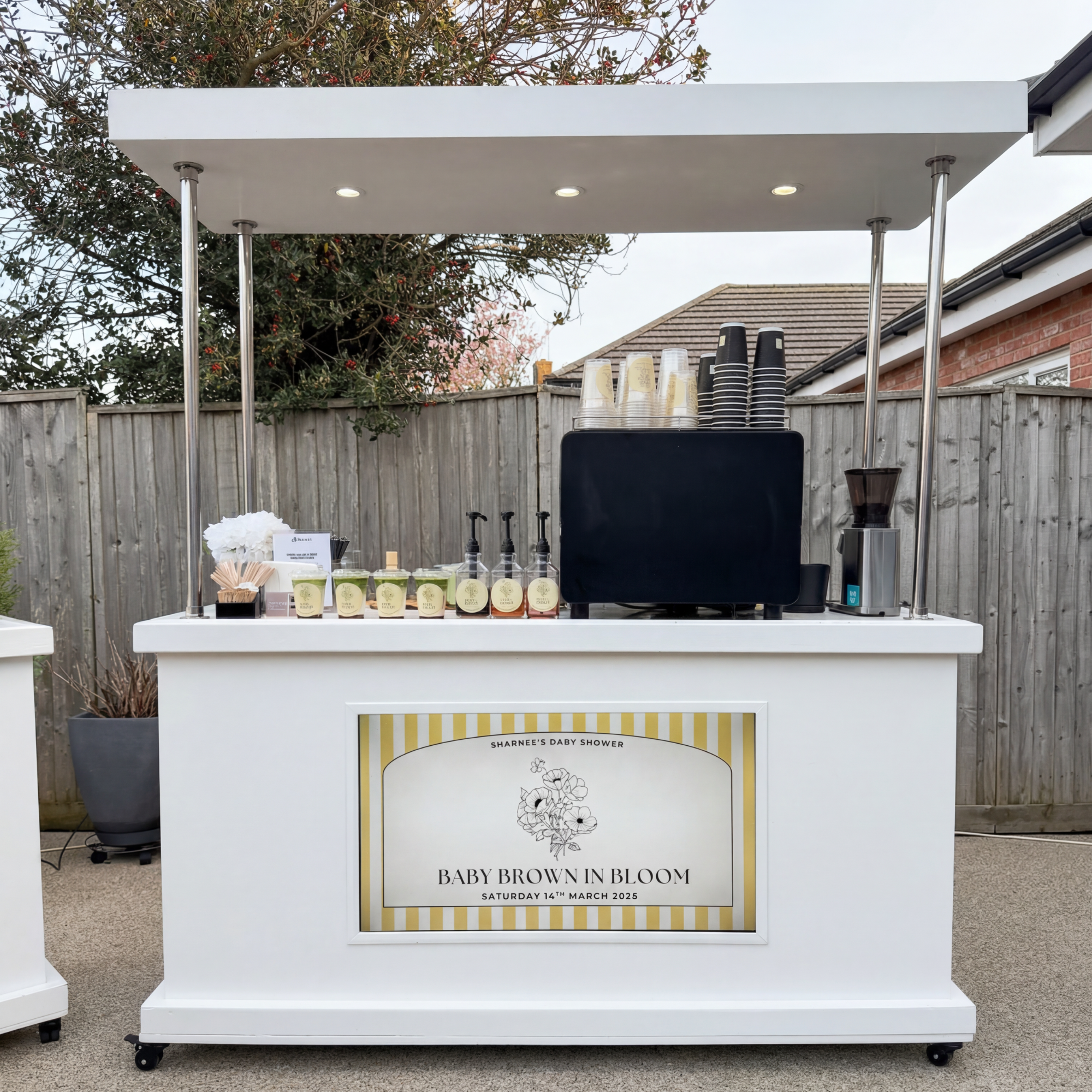 Outdoor coffee and matcha cart with a custom branded sign for a garden baby shower