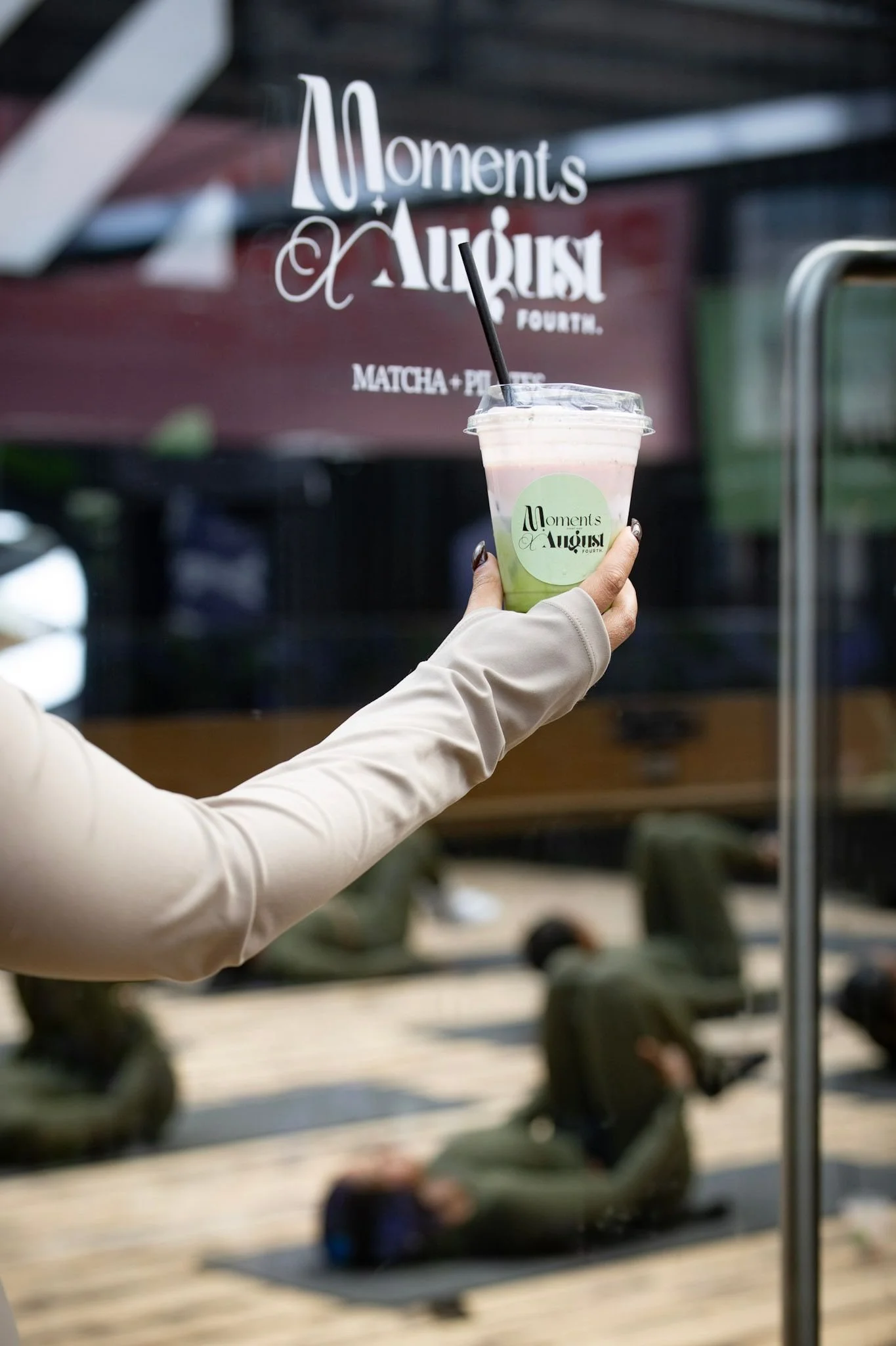Iced strawberry matcha latte at a Moments x August Fourth matcha and Pilates event, with a class in the background