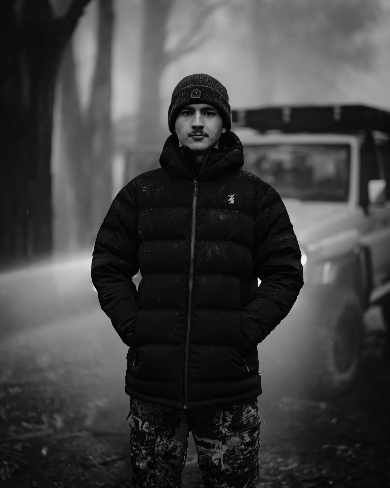 Kyle Wright flow states main videographer  in a black Puffer jacket, patterned pants, and a knitted beanie hat standing outdoors in a foggy environment.