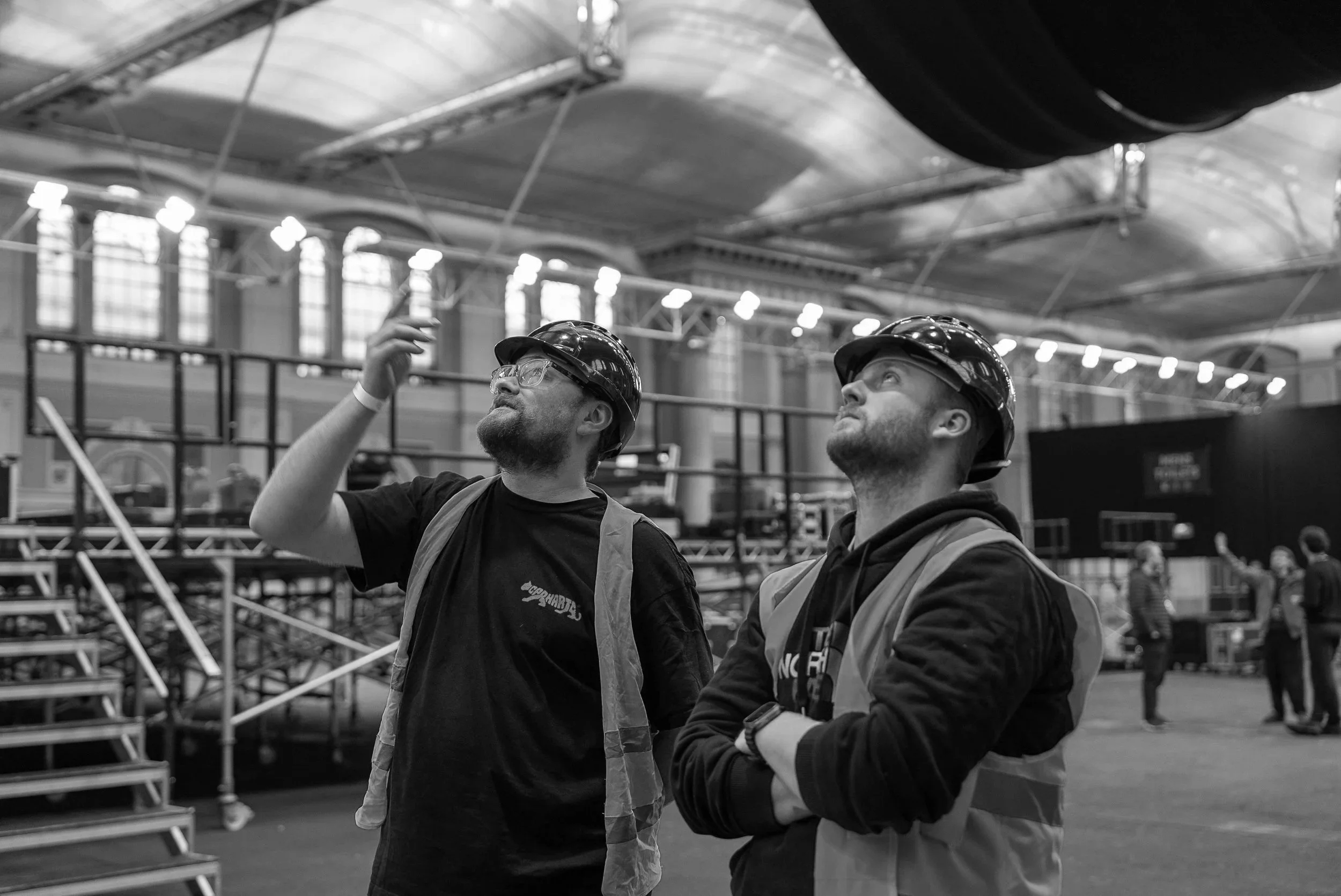 Two crew members on site at a live music event rig