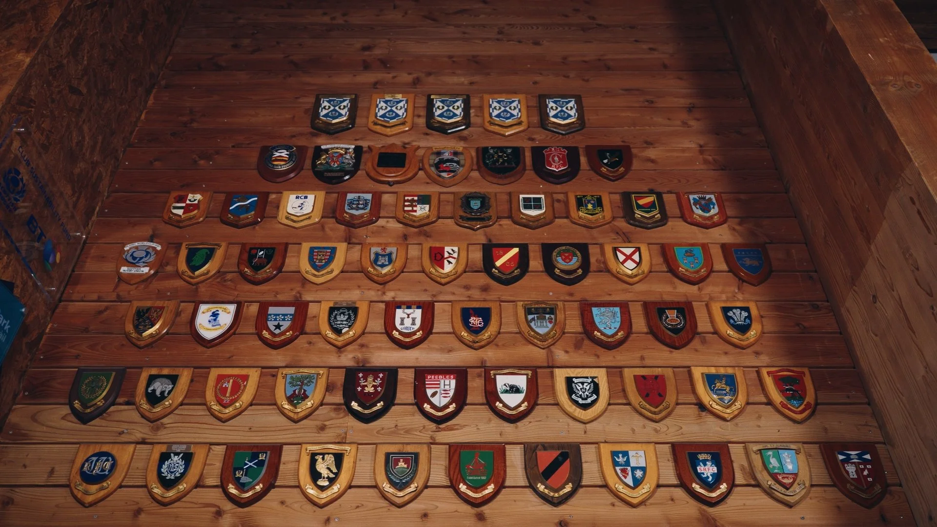 A collection of sports team emblems and badges displayed on a wooden wall.