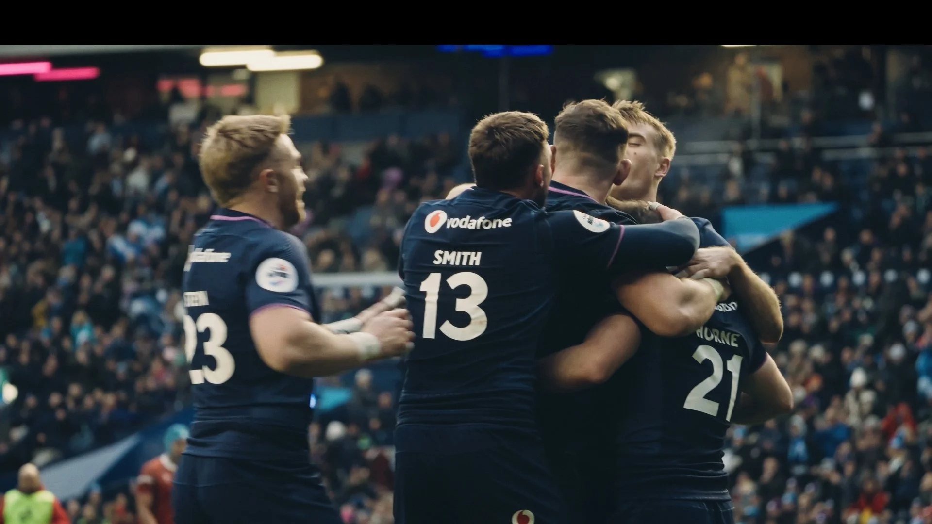 Soccer players celebrating a goal on the field, embracing each other.