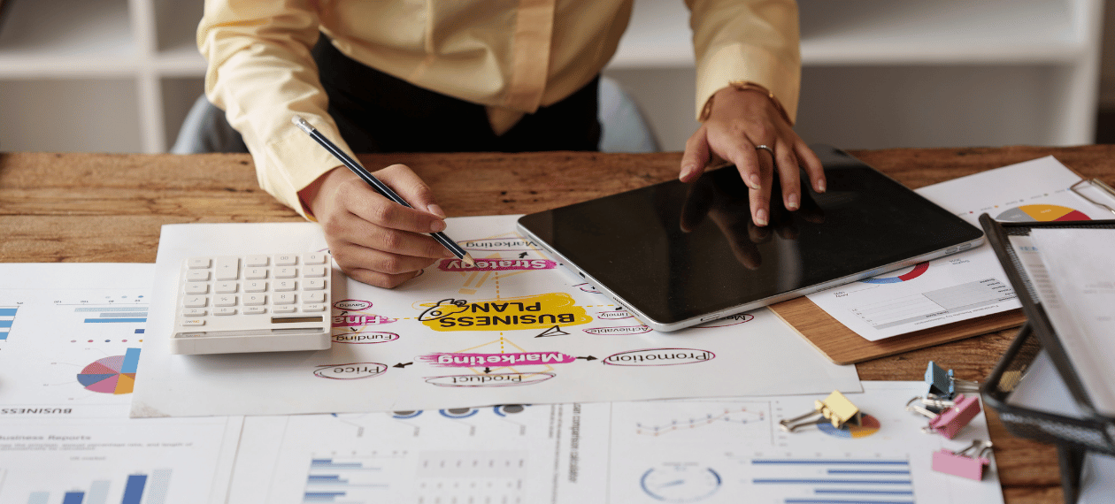 Business owner using a calculator while reviewing financial documents and records