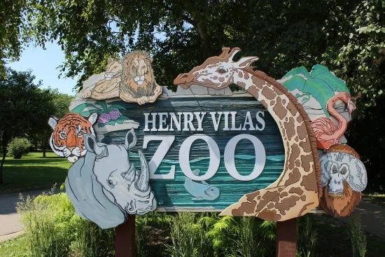 Sign for Henry Vilas Zoo with illustrations of animals including a lion, giraffe, tiger, rhino, sea lion, flamingo, and monkey.