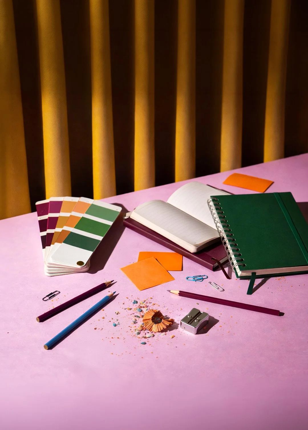 Suunnittelijan työpöytä, jossa muistiinpanovälineitä ja väripaletteja
