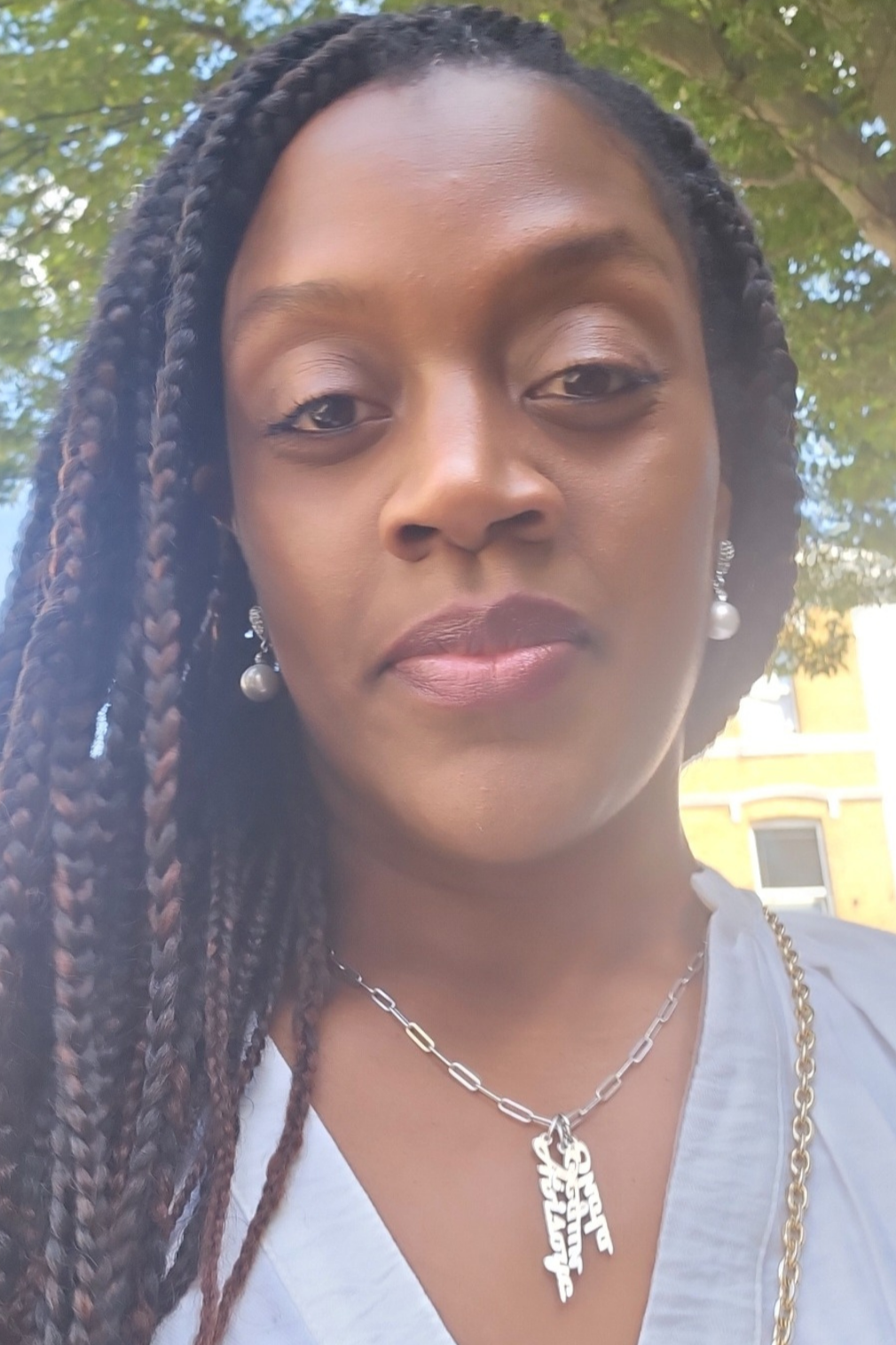 Scenic view of a large turquoise lake surrounded by rolling green hills and tall mountains in the background, under a cloudy sky.