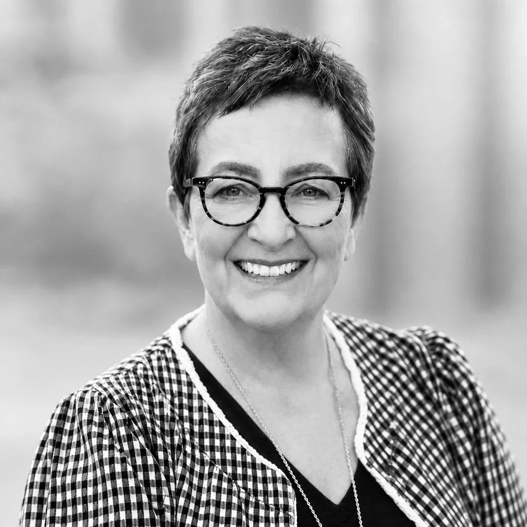 A black and white photo of a woman with short hair smiling at the camera.