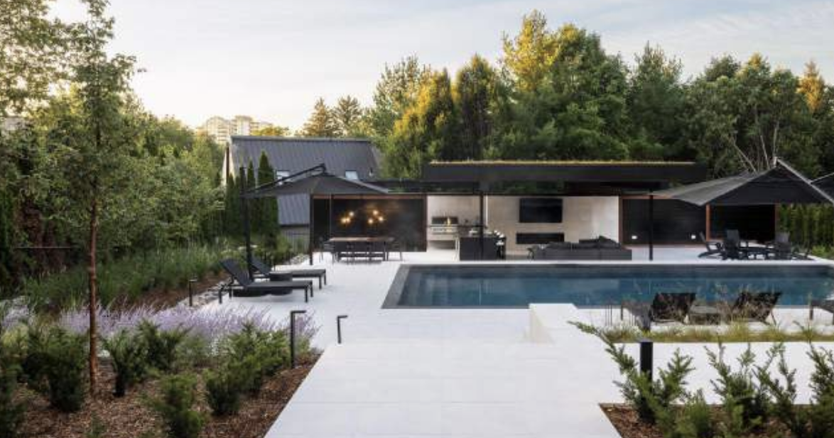 Modern luxury backyard with custom swimming pool, large concrete patio, and outdoor living pavilion as part of a Toronto landscape design.