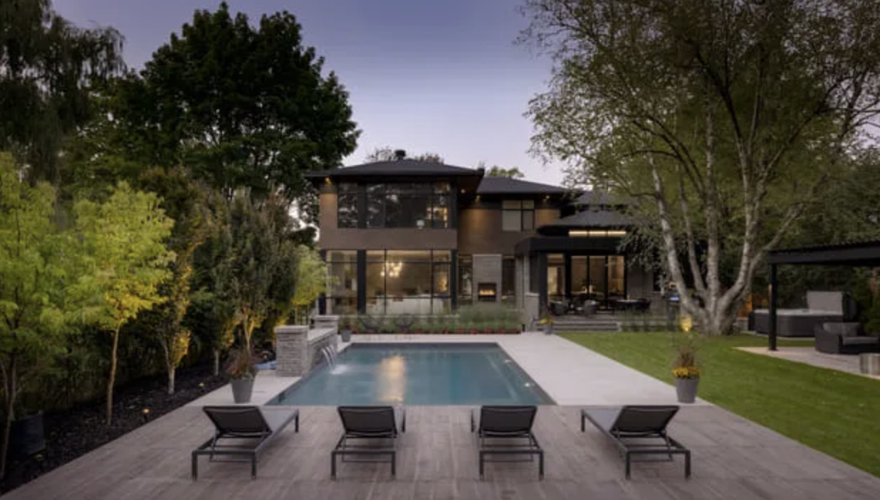Modern home with symmetrical backyard pool, lounge seating, and premium stone patio designed for upscale Toronto outdoor living.