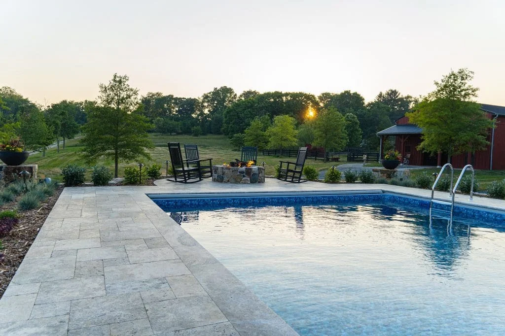 Backyard swimming pool surrounded by natural stone patio and open landscape views, designed for relaxed outdoor living.