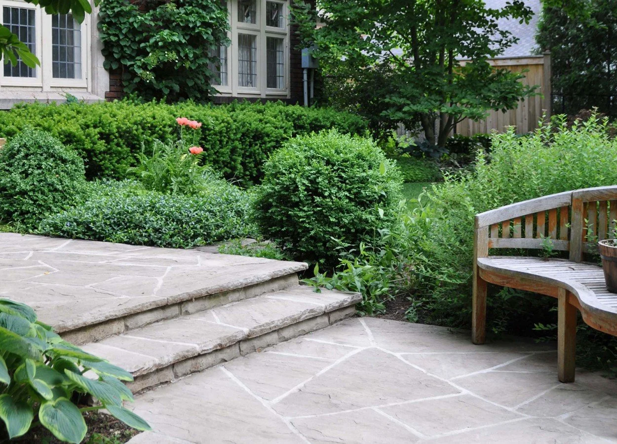 Natural stone garden steps leading into a lush front yard landscape with shrubs and greenery.