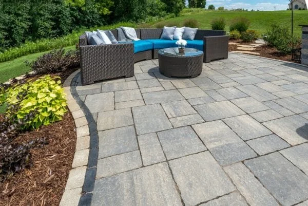 Interlocking stone patio with outdoor seating area in a landscaped backyard